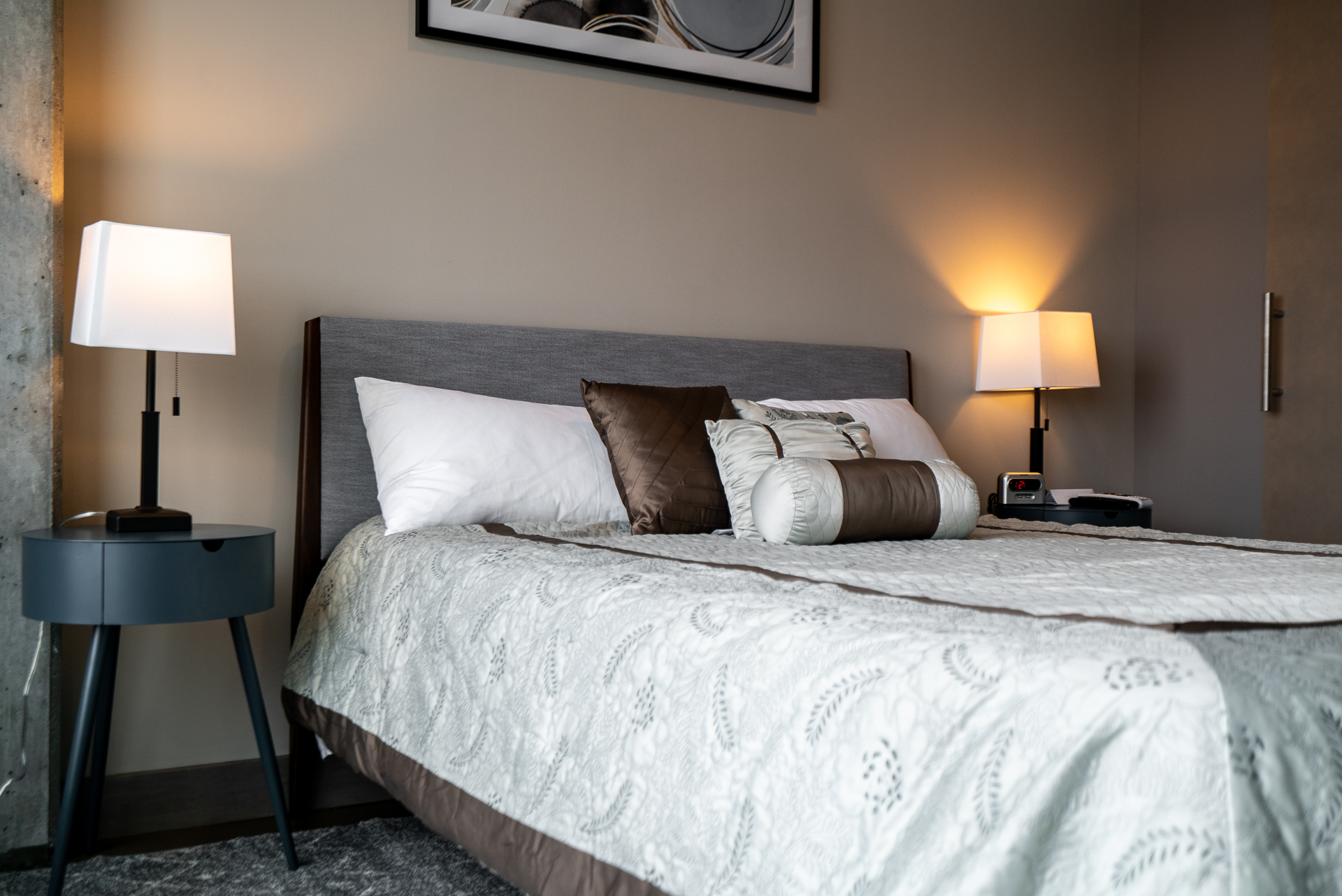 A modern bedroom featuring a cozy bed with elegant bedding and stylish bedside lamps.