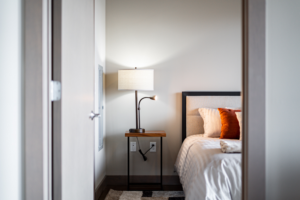 A cozy bedroom corner featuring a stylish lamp and a neatly made bed.