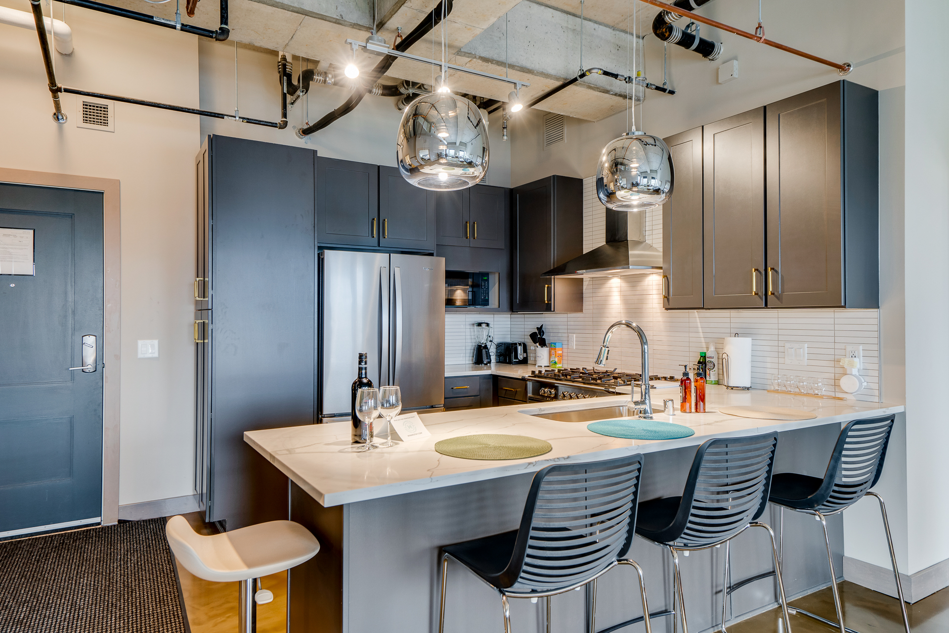 A contemporary kitchen with dark cabinets and a marble countertop featuring stylish pendant lighting.