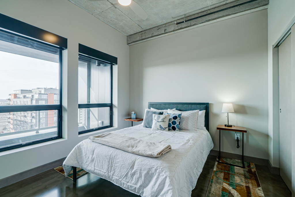 A modern bedroom with stunning city views, featuring soft colors and minimalist design.