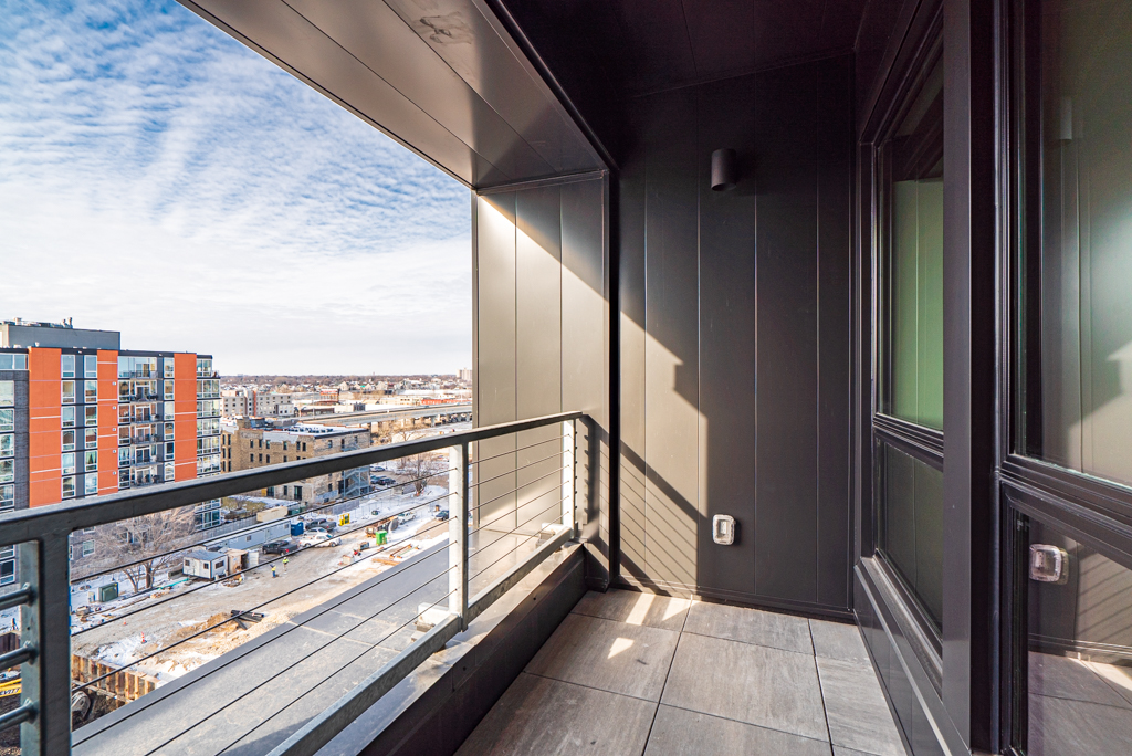 A modern balcony with a striking cityscape view, showcasing elegant design and bright sunlight.