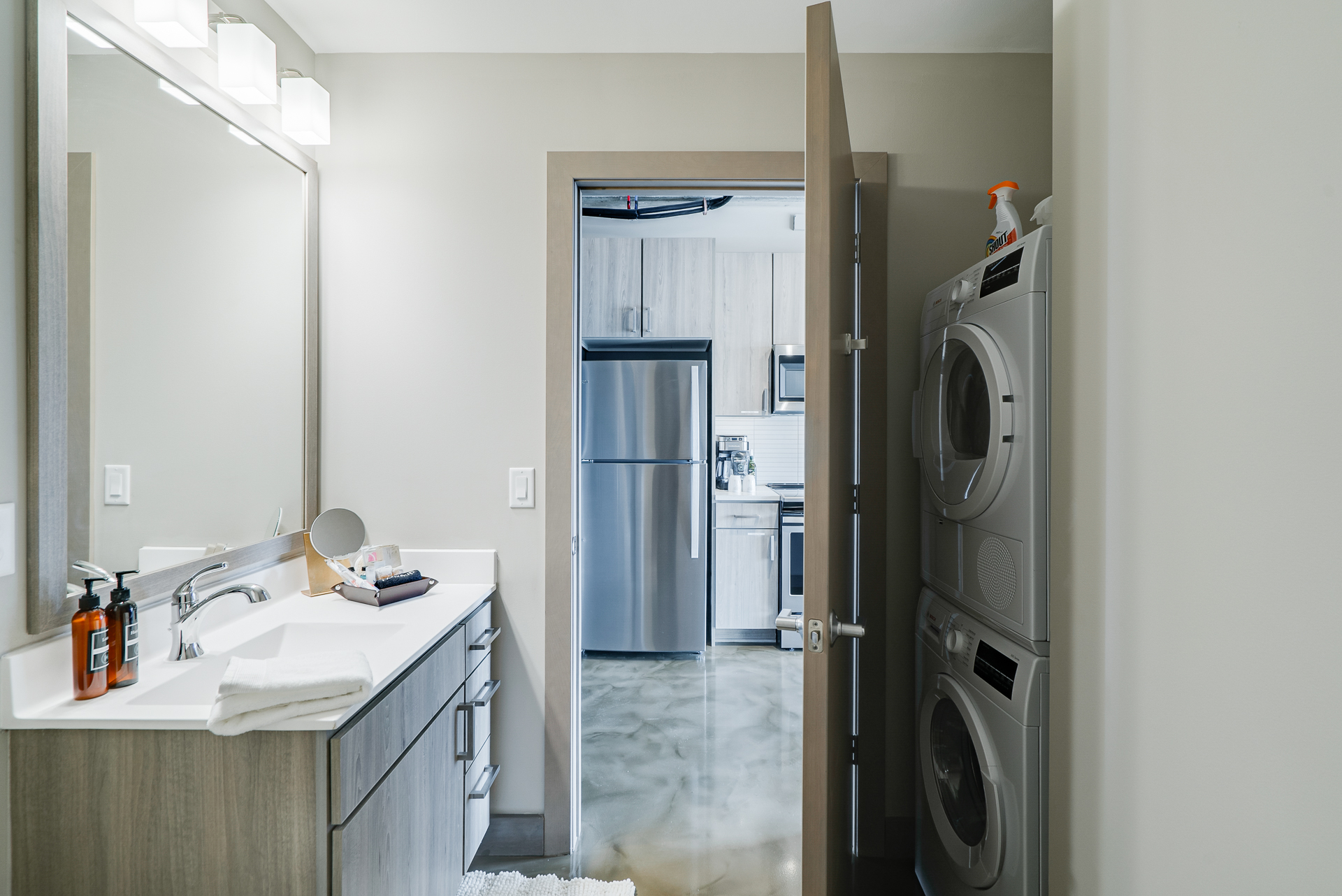 A modern bathroom with an adjoining laundry area and kitchen.