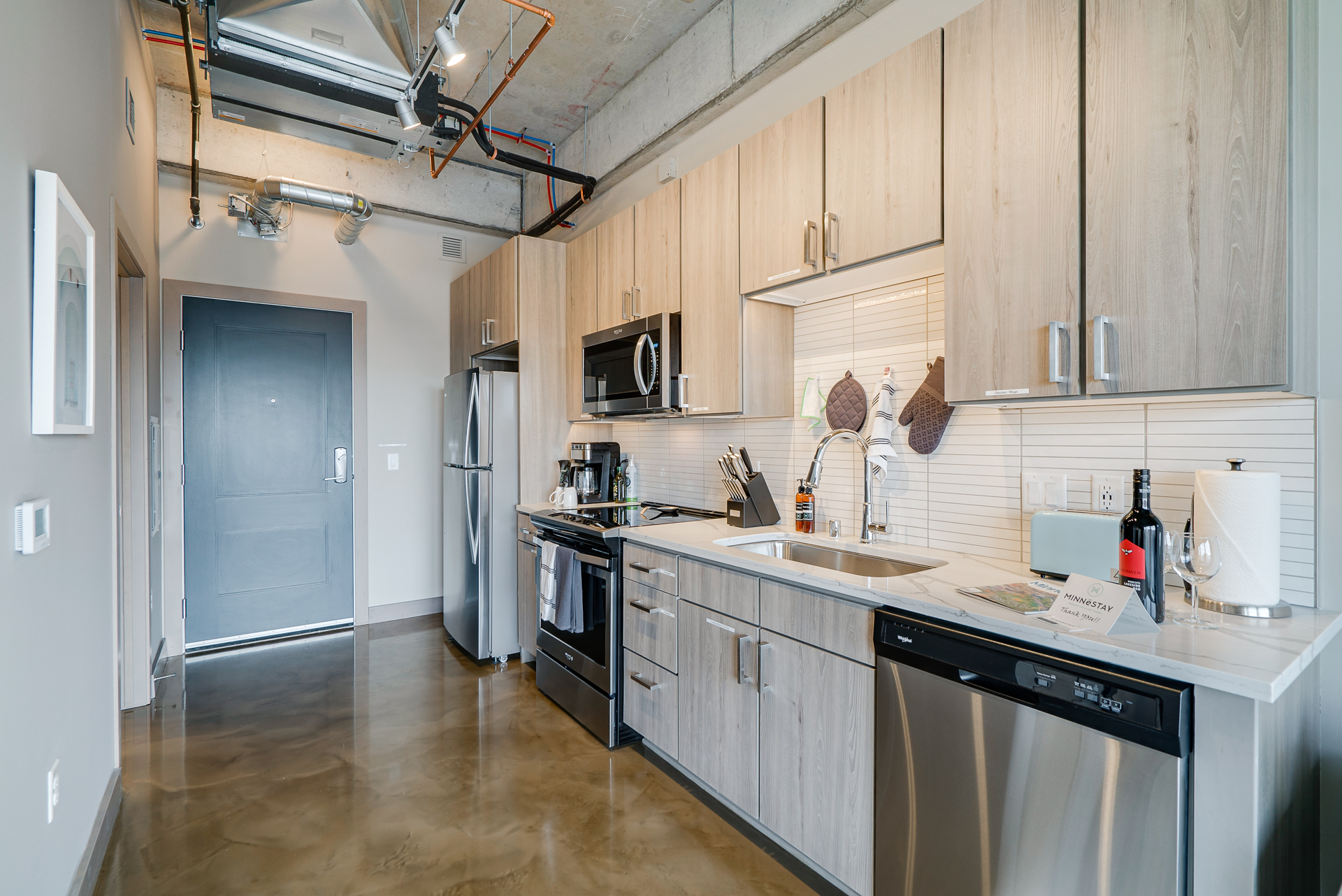 A stylish modern kitchen featuring light wood cabinetry and stainless steel appliances.