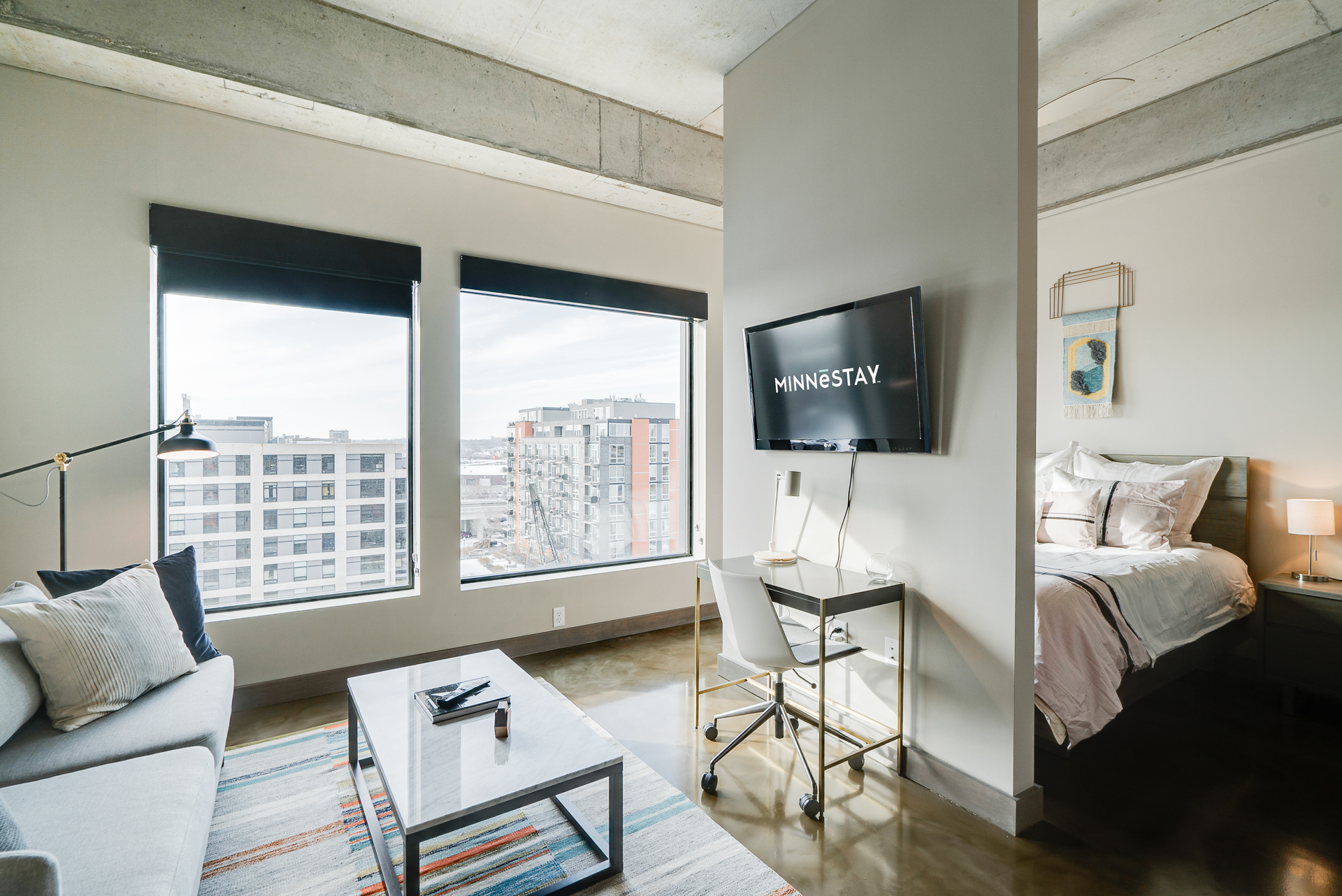 Modern studio apartment with a cozy seating area, desk, and bedroom.