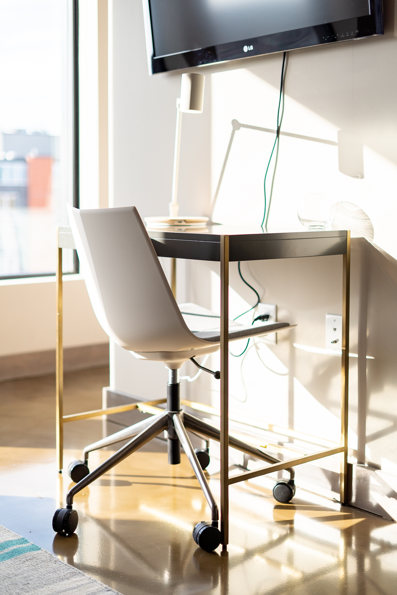 A stylish minimalist workspace with a modern desk and chair, illuminated by natural light.