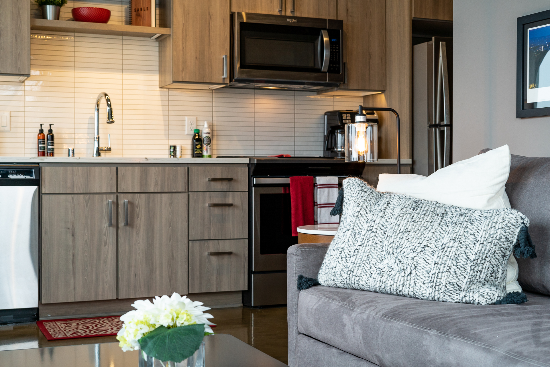 A cozy and modern kitchen-living area featuring gray cabinetry and stylish decor.