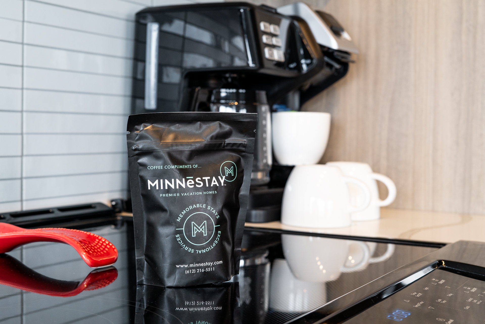 A stylish kitchen with complimentary coffee from MINNESTAY, featuring a sleek coffee maker and white mugs.