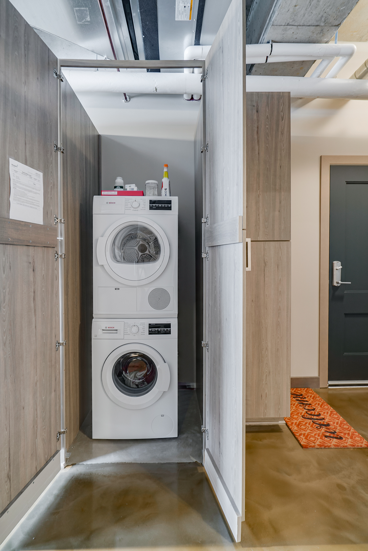 A modern laundry area featuring a stacked washer and dryer with elegant wooden doors.