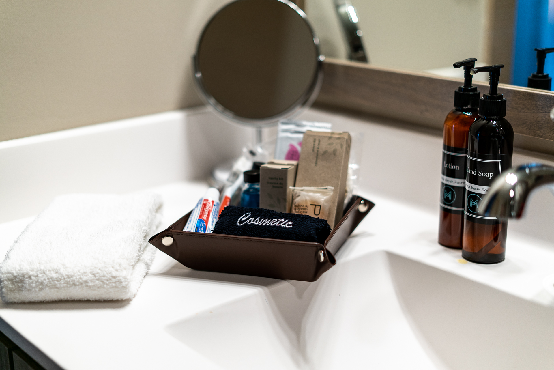 A well-organized bathroom countertop featuring toiletries and a neatly folded towel.