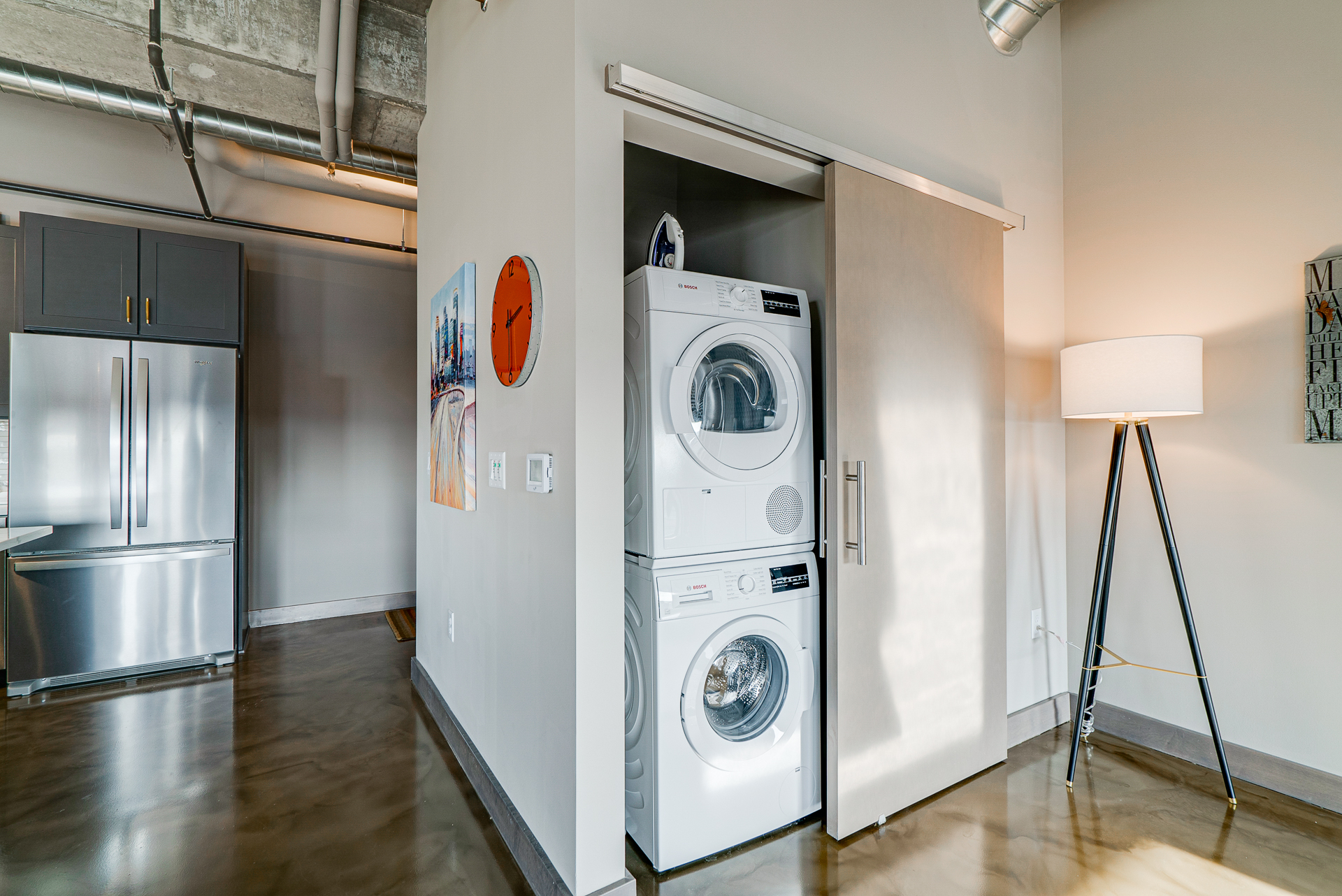 A modern laundry space integrated within an apartment, featuring a stacked washer and dryer with stylish decor.
