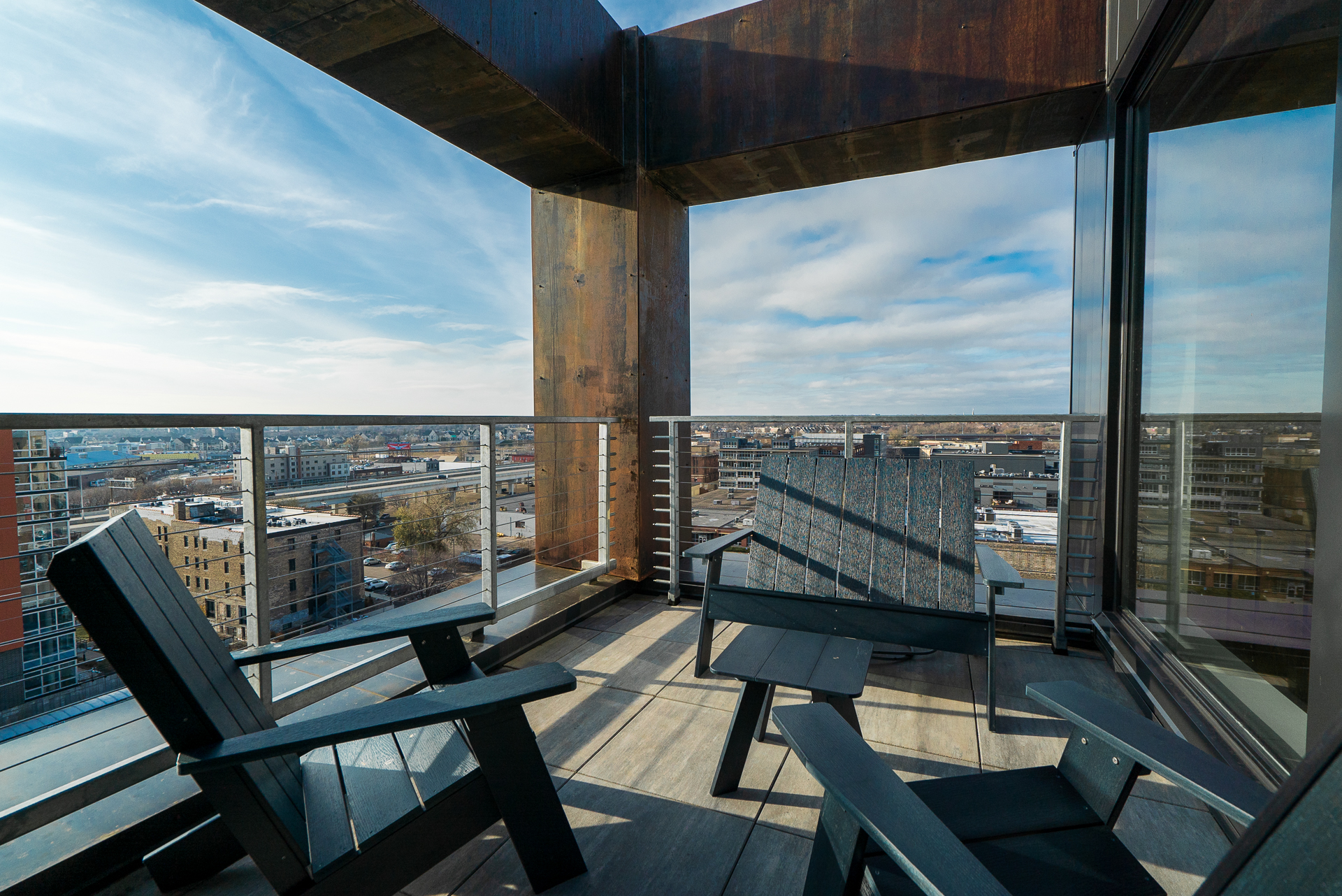 A modern balcony featuring Adirondack chairs with a stunning city view.