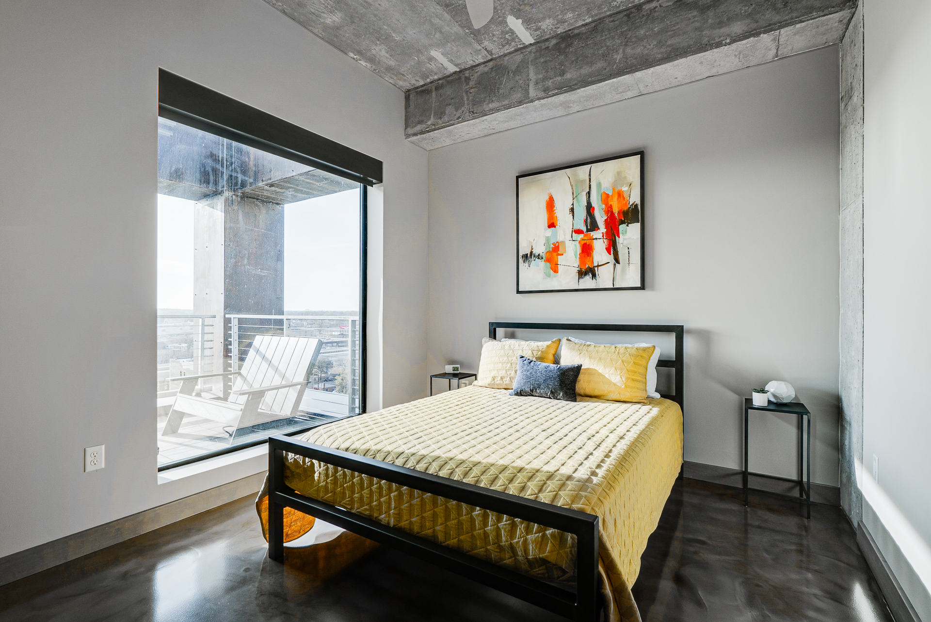 A modern bedroom designed with a yellow quilt and abstract art.