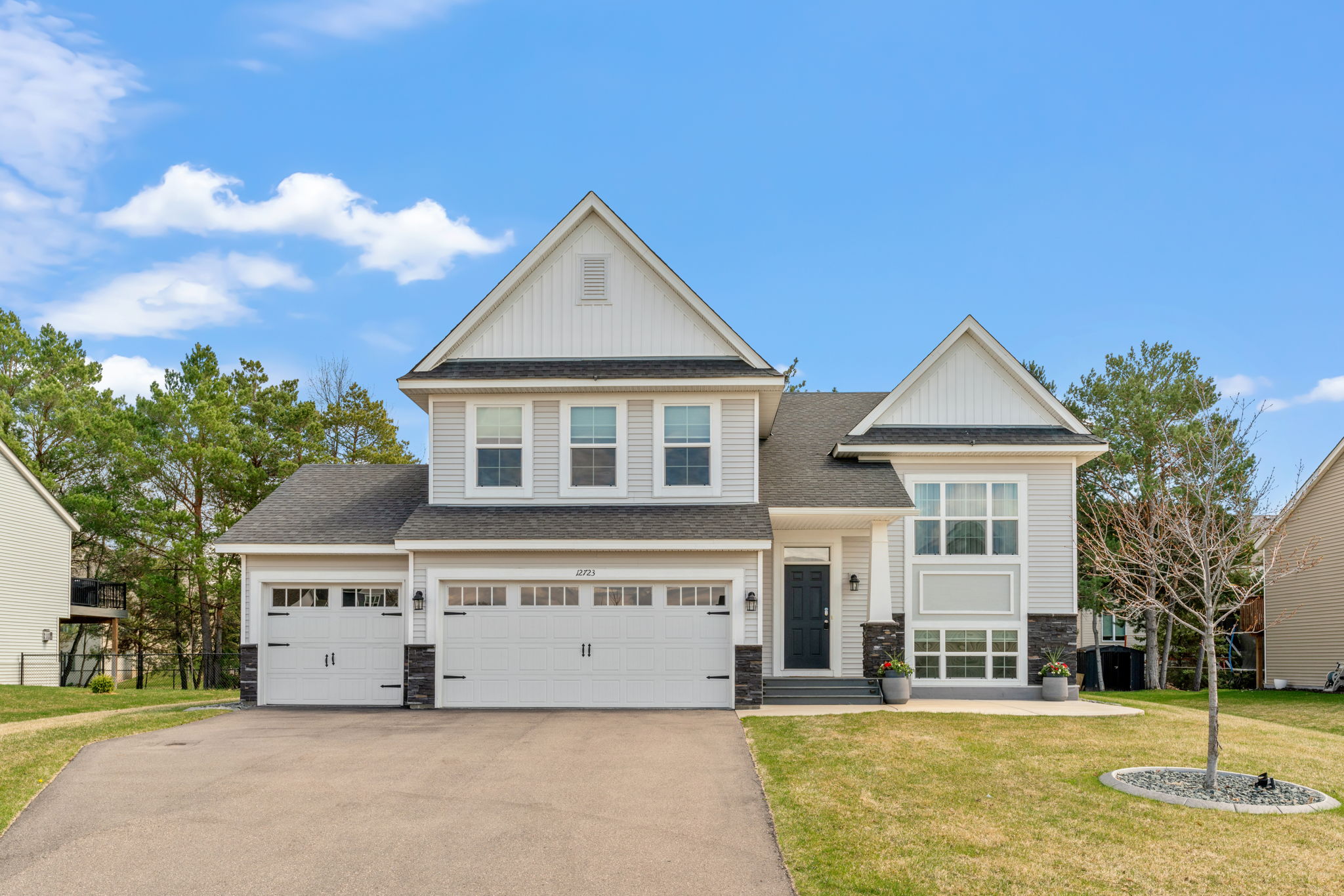 A charming suburban home featuring a stylish facade with stone accents and a well-manicured front yard.