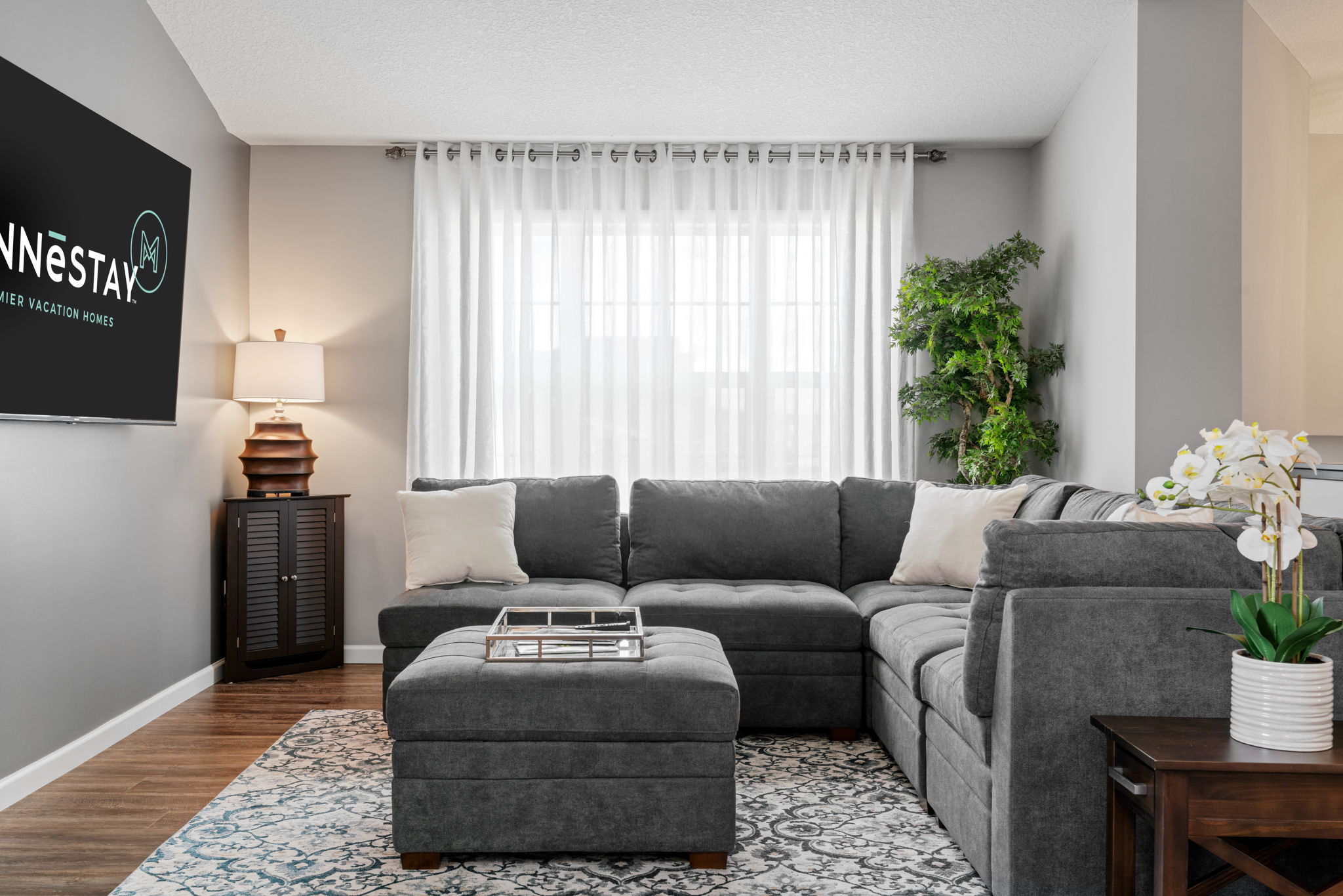 A stylish living room featuring a gray sectional sofa and bright natural light.
