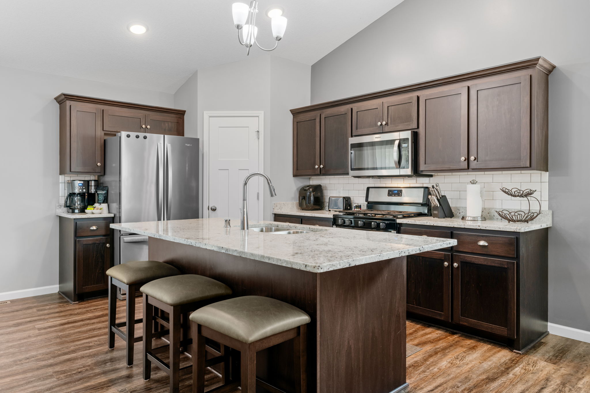 A modern kitchen featuring dark cabinetry and light granite countertops.