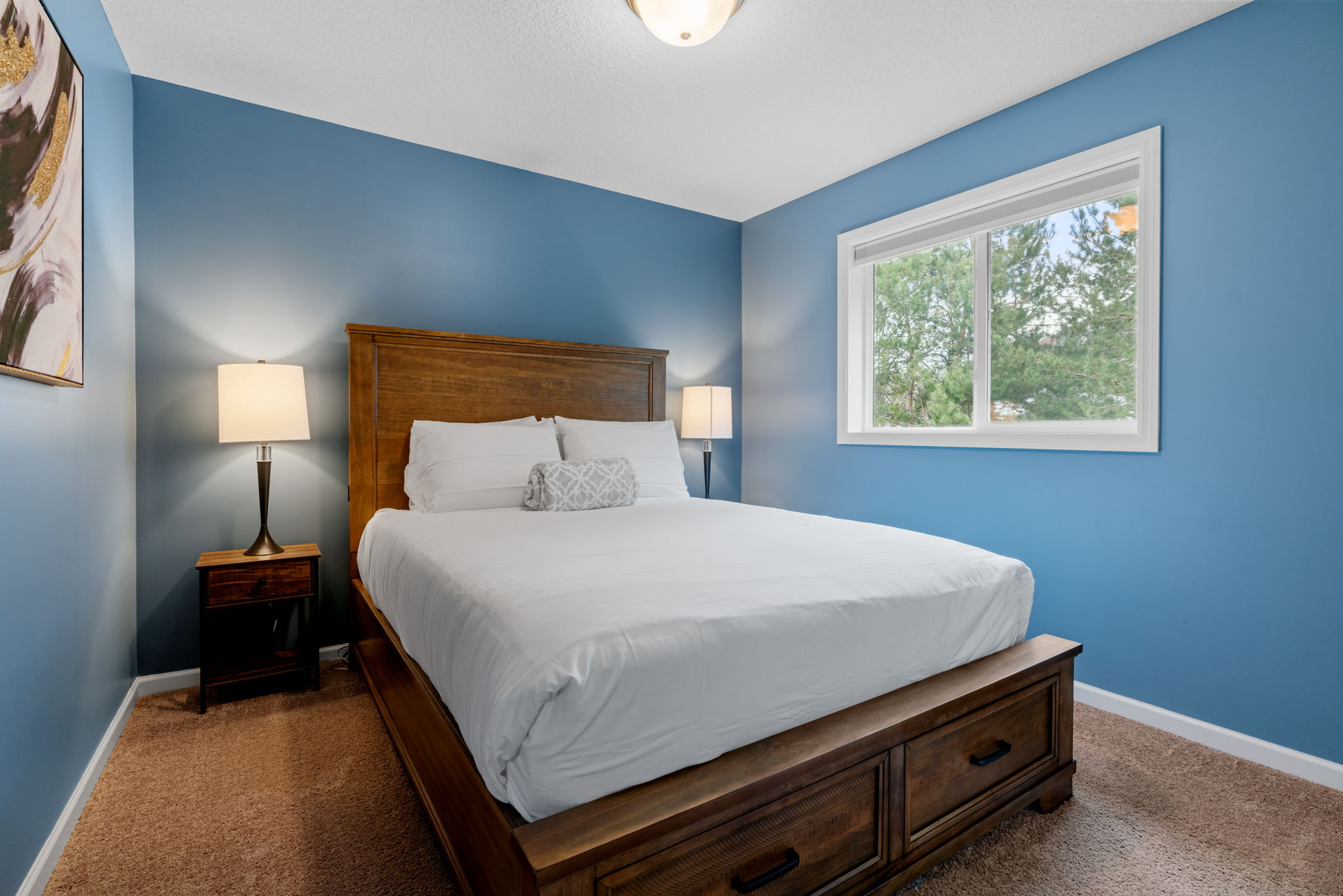 A cozy bedroom featuring a blue wall, wooden bed, and soft lighting.