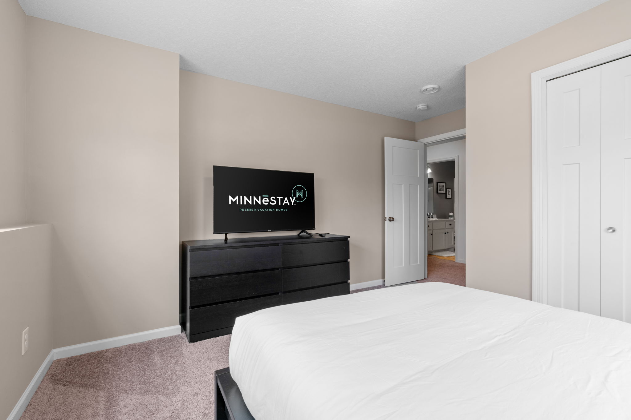 A modern bedroom featuring a flat-screen TV and a stylish dresser.