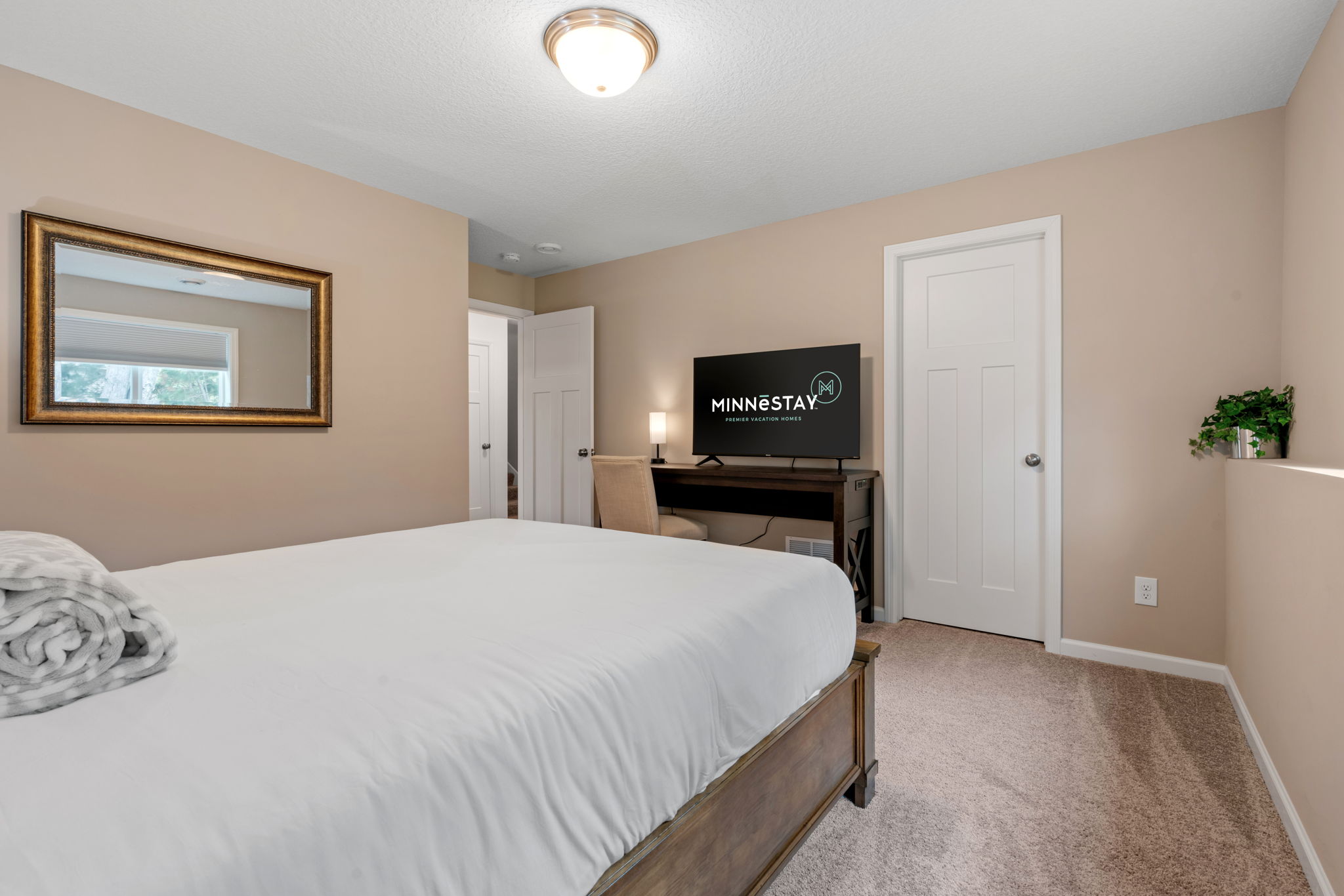A serene bedroom featuring a cozy bed, modern amenities, and warm decor.