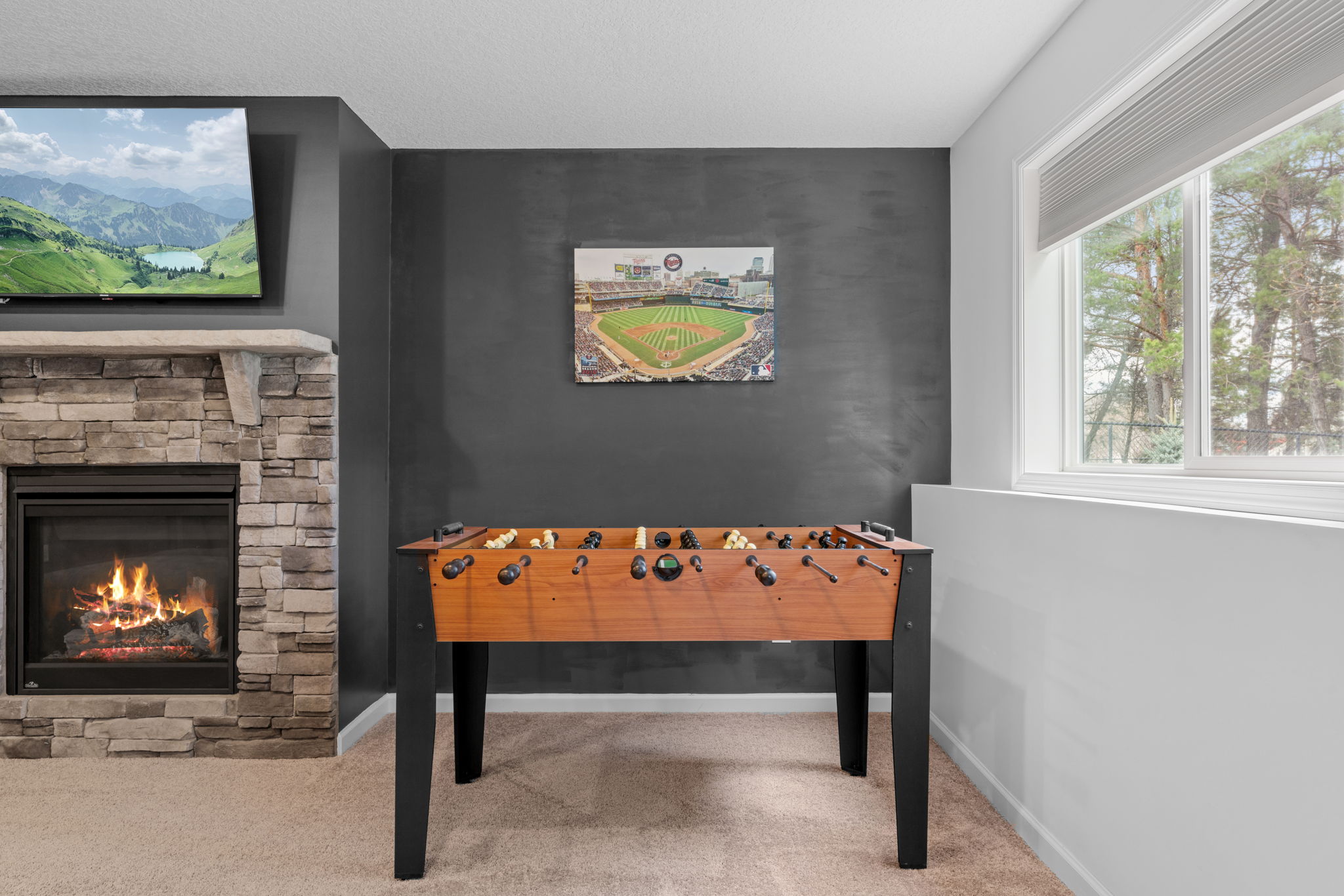 A cozy game room with a foosball table, stone fireplace, and stunning artwork.