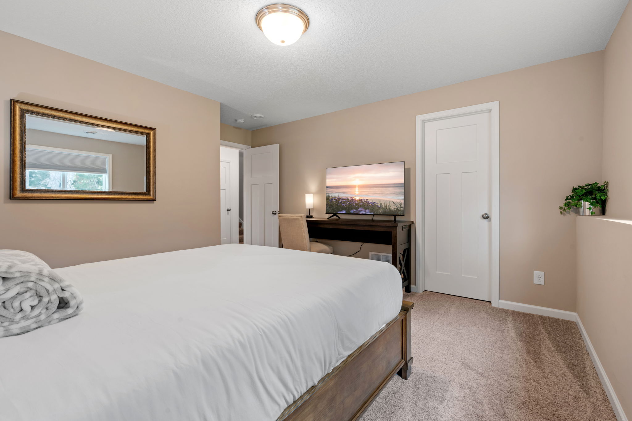 A cozy bedroom with modern touches, featuring a neat bed and a workspace.