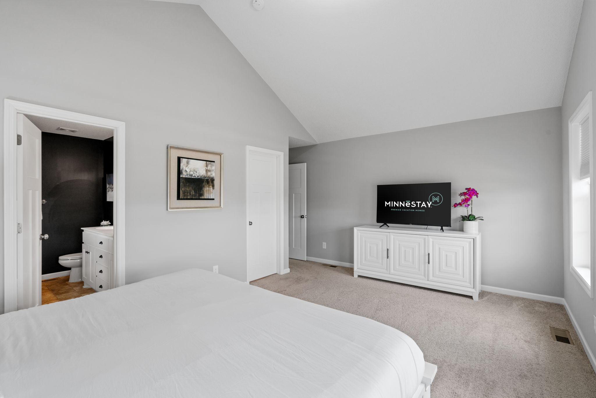 A modern and inviting bedroom with a high ceiling and minimalist decor.