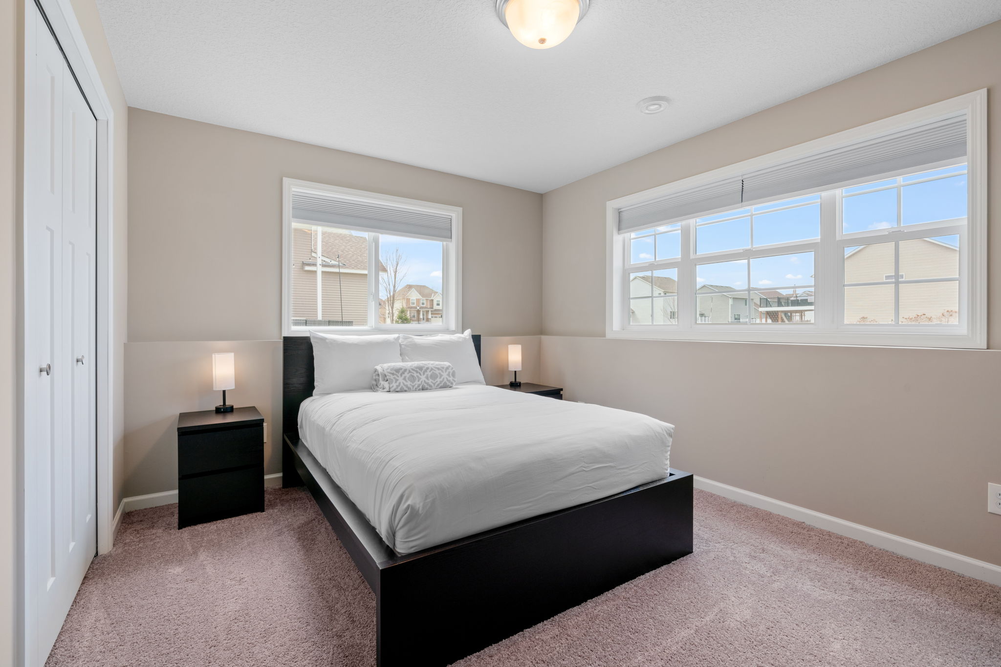 A modern, cozy bedroom featuring minimalist decor and ample natural light.