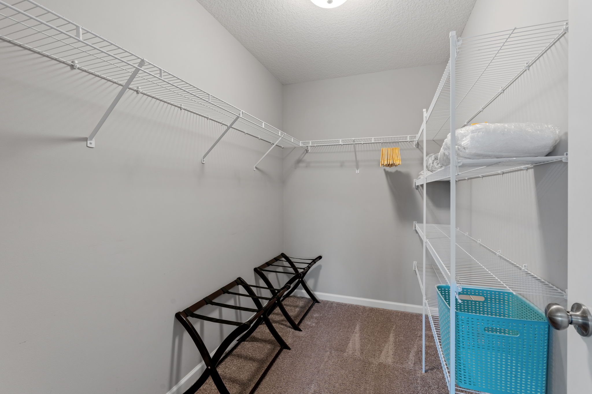 An organized closet with wire shelving, seating, and storage options.