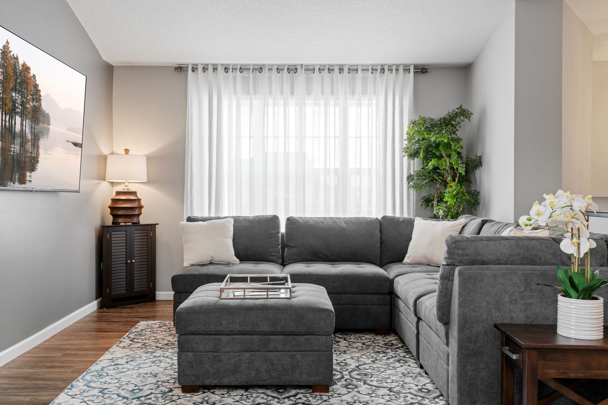 A modern and cozy living room featuring a gray sectional sofa and calming decor.