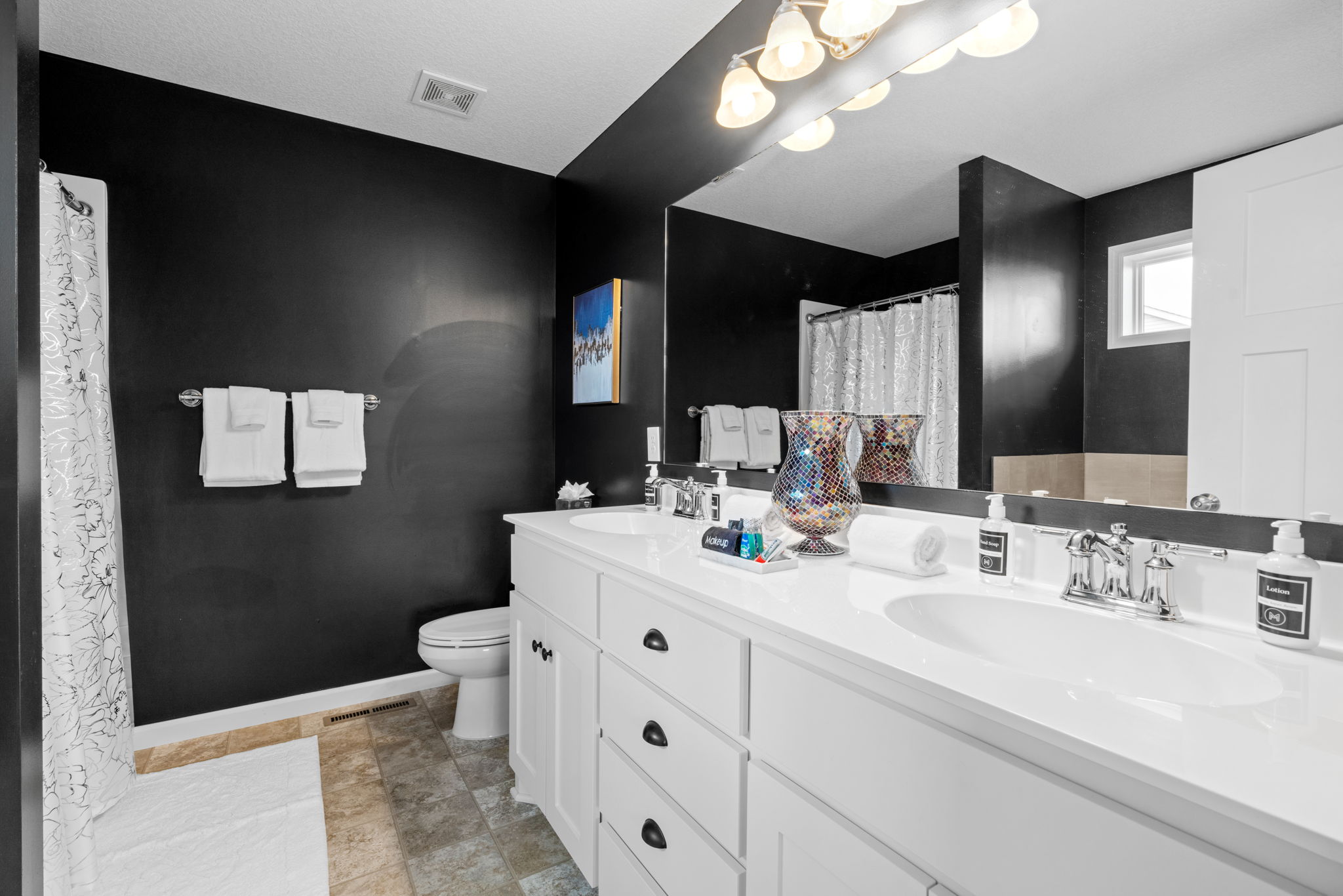A modern bathroom with dark walls and a contrasting white vanity.