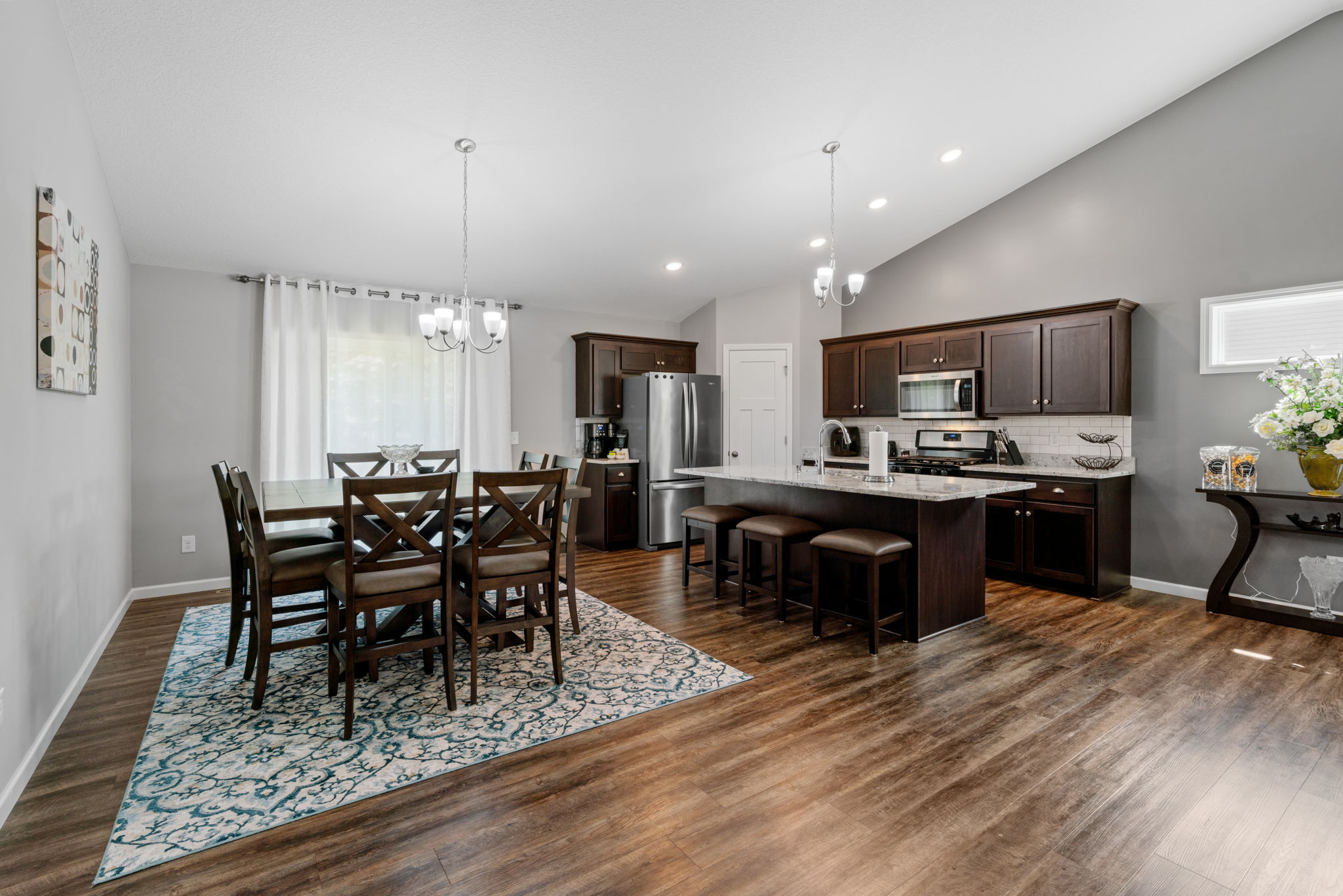 A contemporary kitchen and dining area featuring dark wood, elegant decor, and modern appliances.