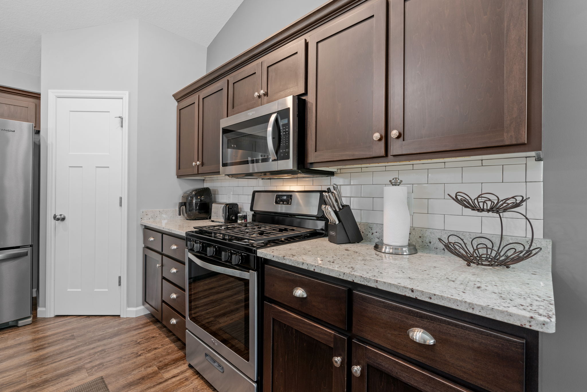 A modern kitchen featuring dark wood cabinets and stainless steel appliances.
