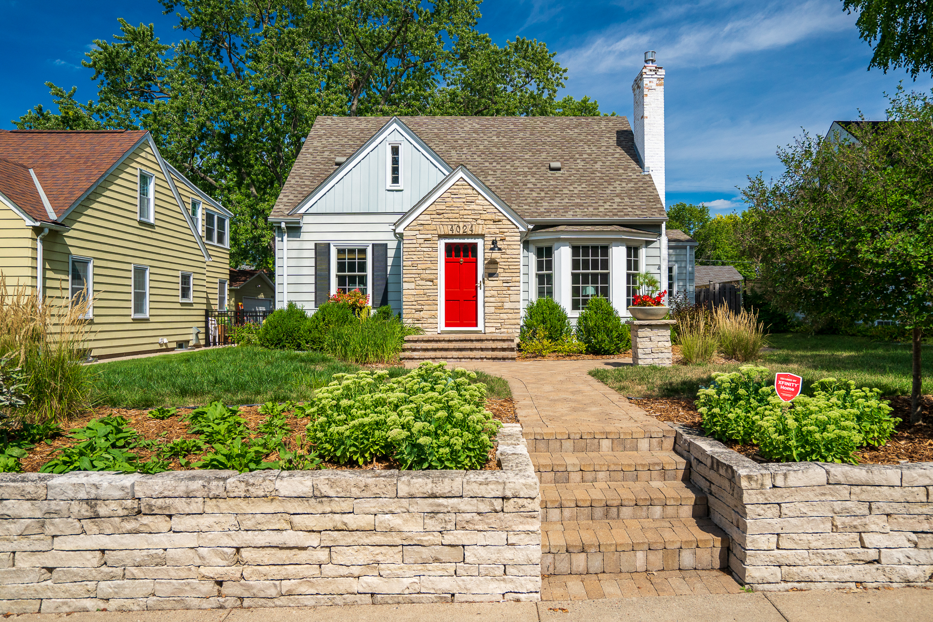 Charming suburban home with a red door and lush landscaping.
