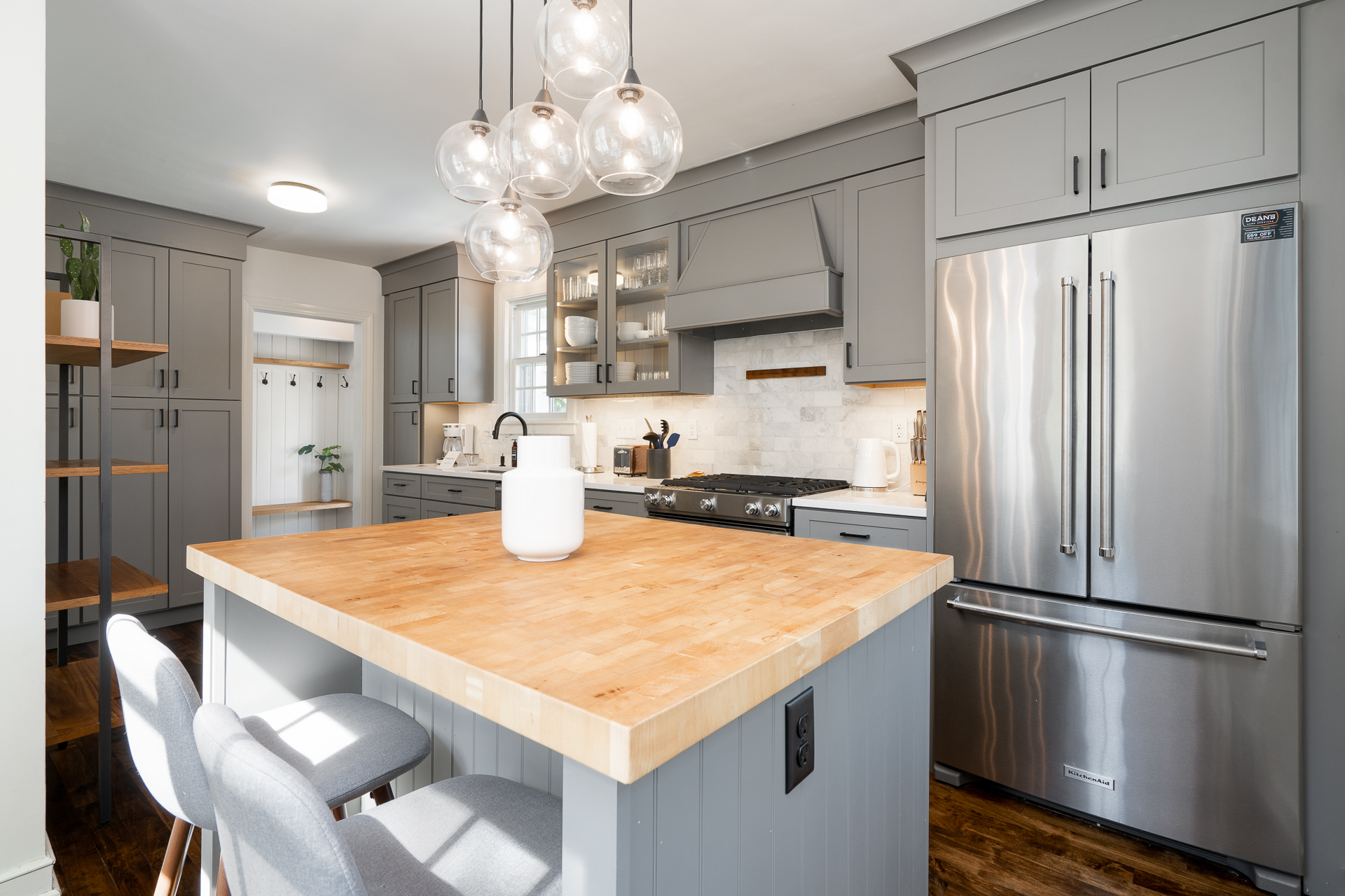 A modern kitchen with gray cabinetry and a light wood island.