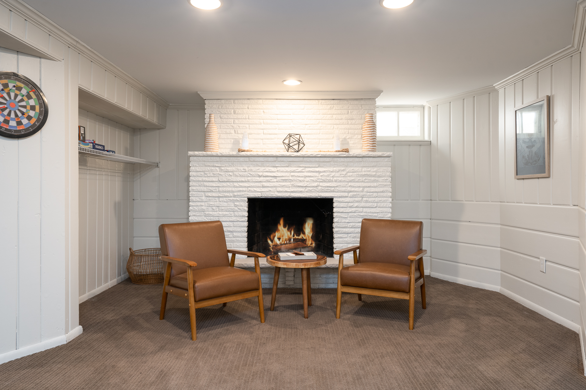 A cozy living space featuring mid-century armchairs and a white brick fireplace.
