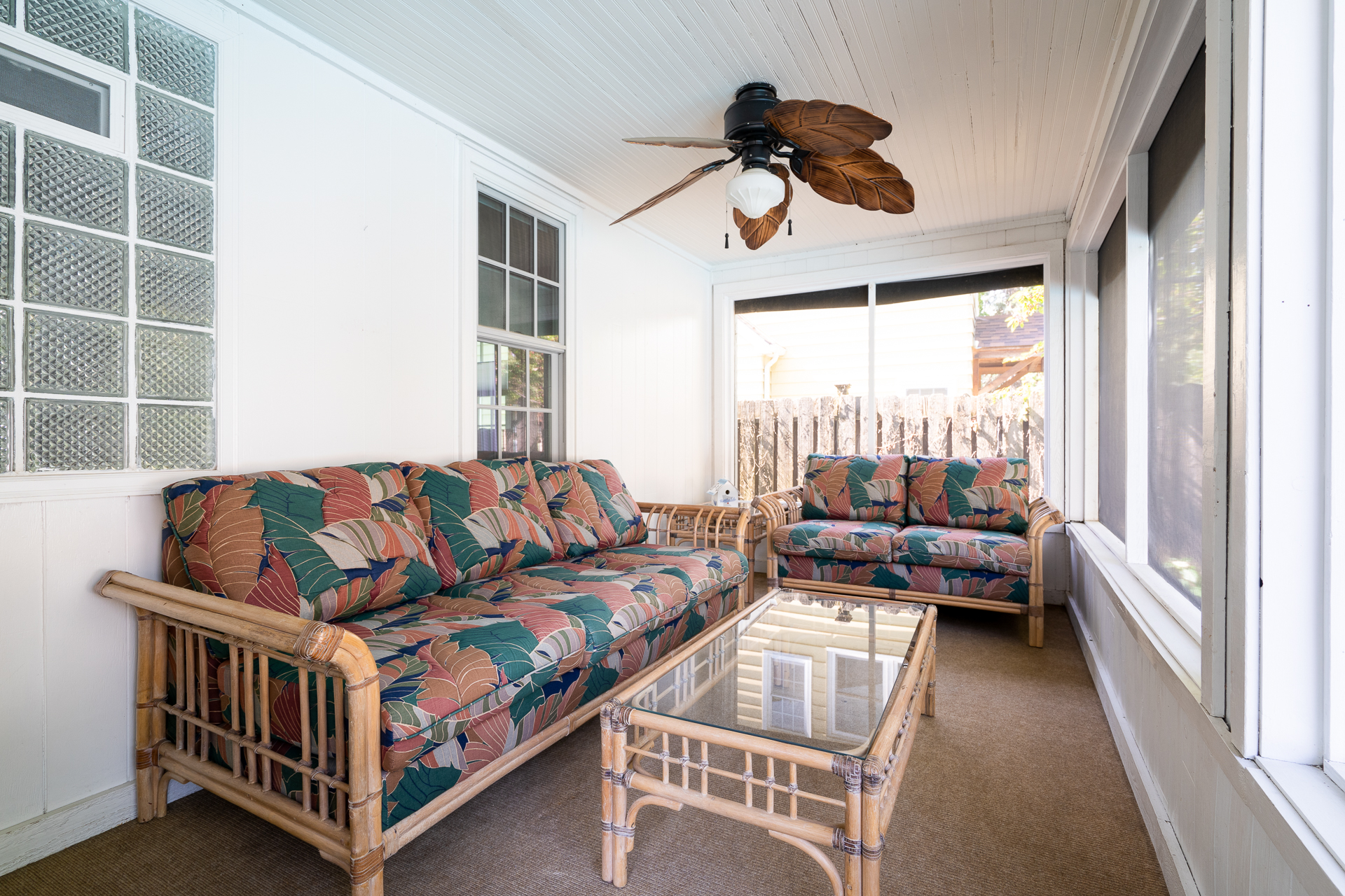 A cozy sunroom with tropical-print sofas and light natural decor.