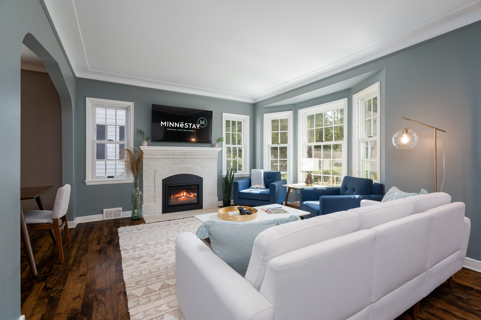 Cozy living room with a white sofa, blue armchairs, and a fireplace.