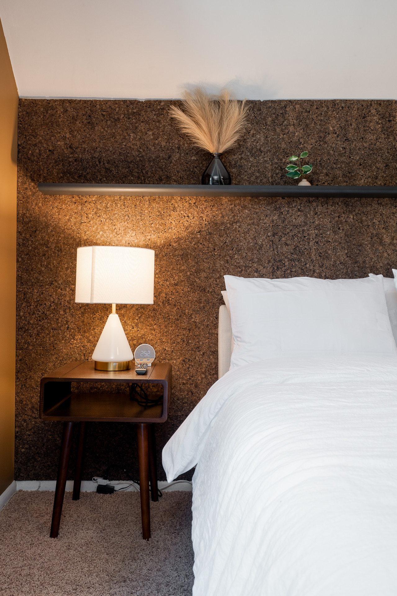 A modern bedroom with a cozy atmosphere featuring a cork wall, stylish decor, and a comfortable bed.