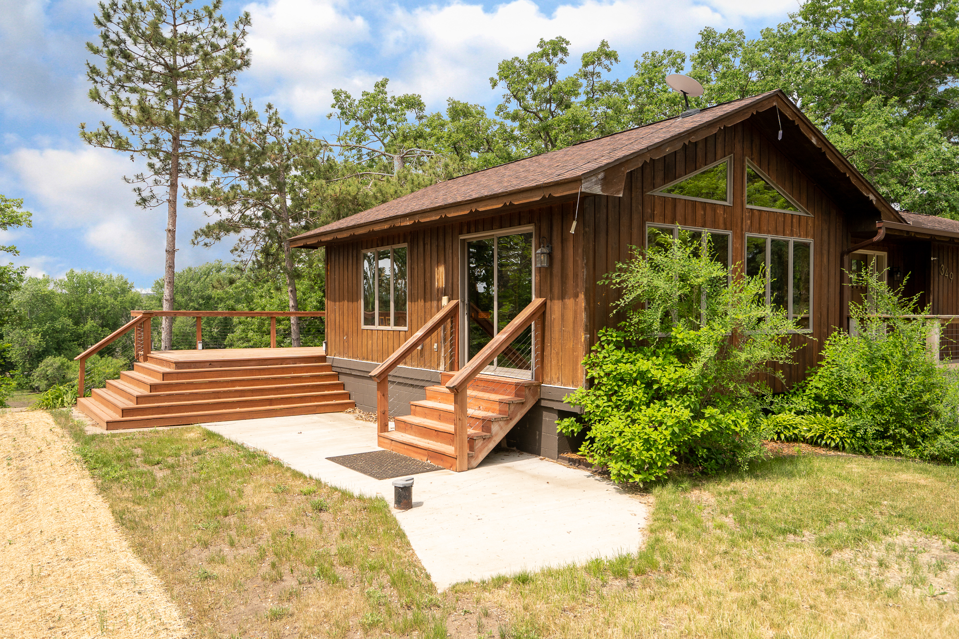 A charming wooden house with a spacious deck surrounded by greenery.