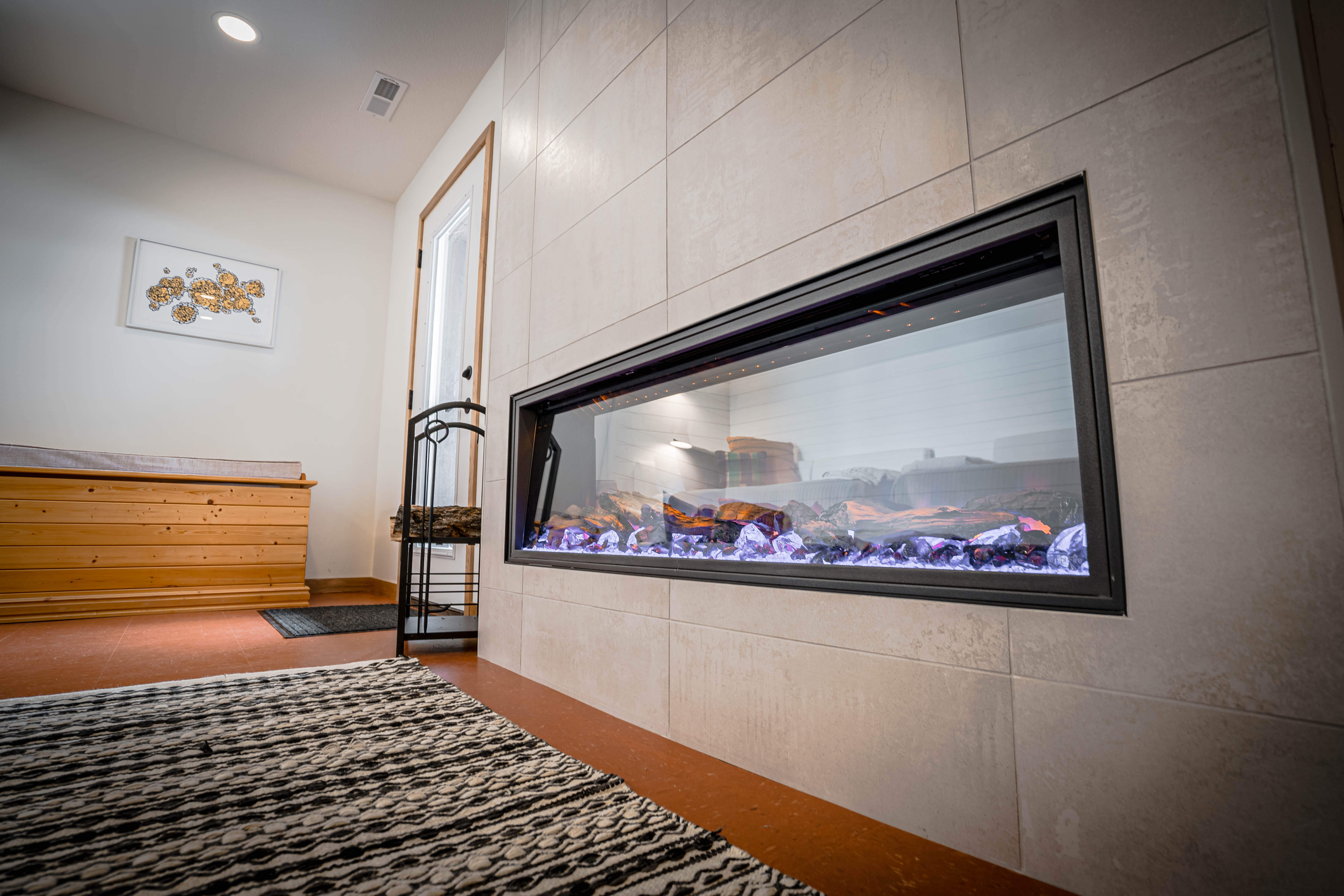 Modern linear fireplace with vibrant glowing crystals in a cozy interior.