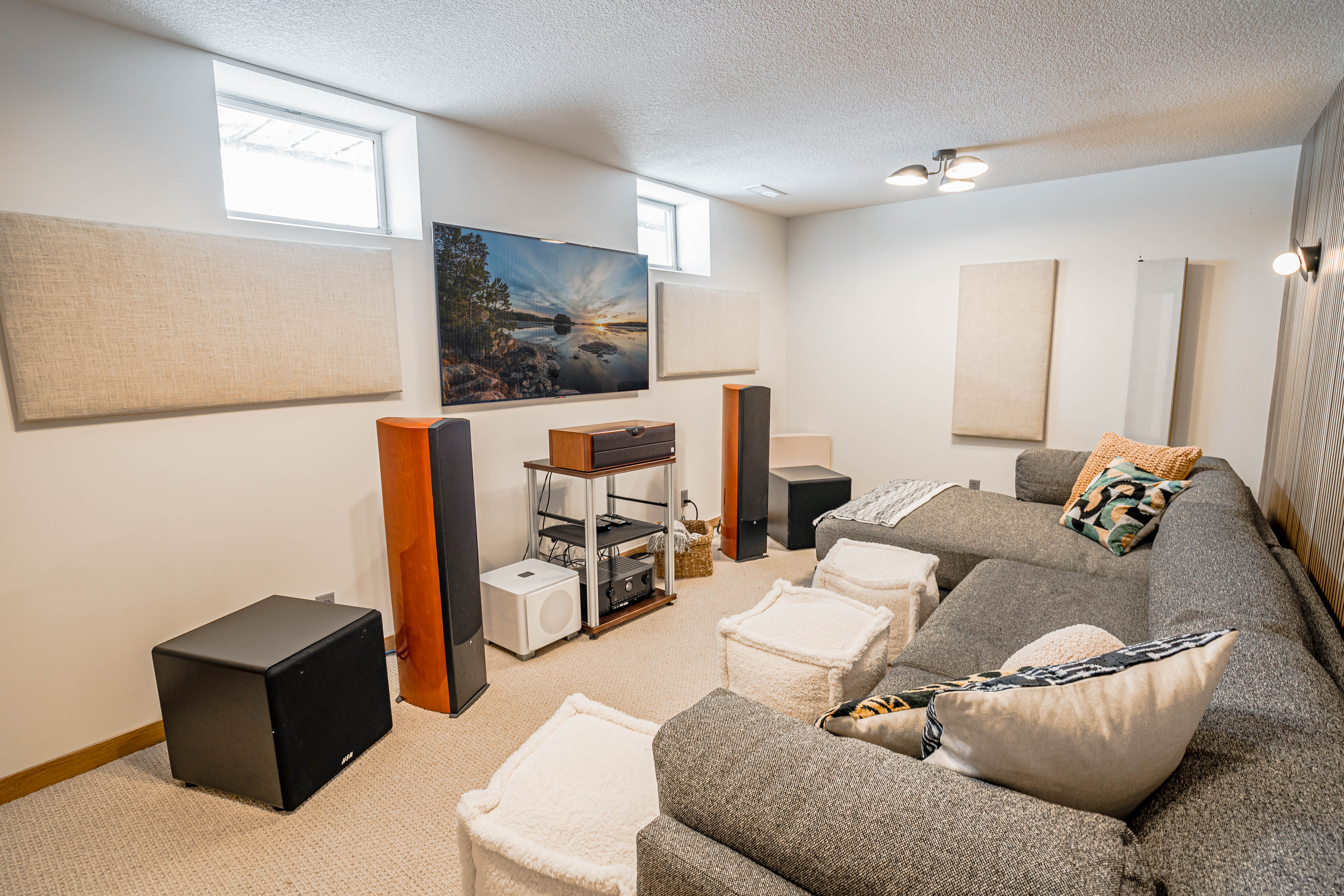 A cozy basement entertainment room featuring a gray sectional sofa and audio equipment.