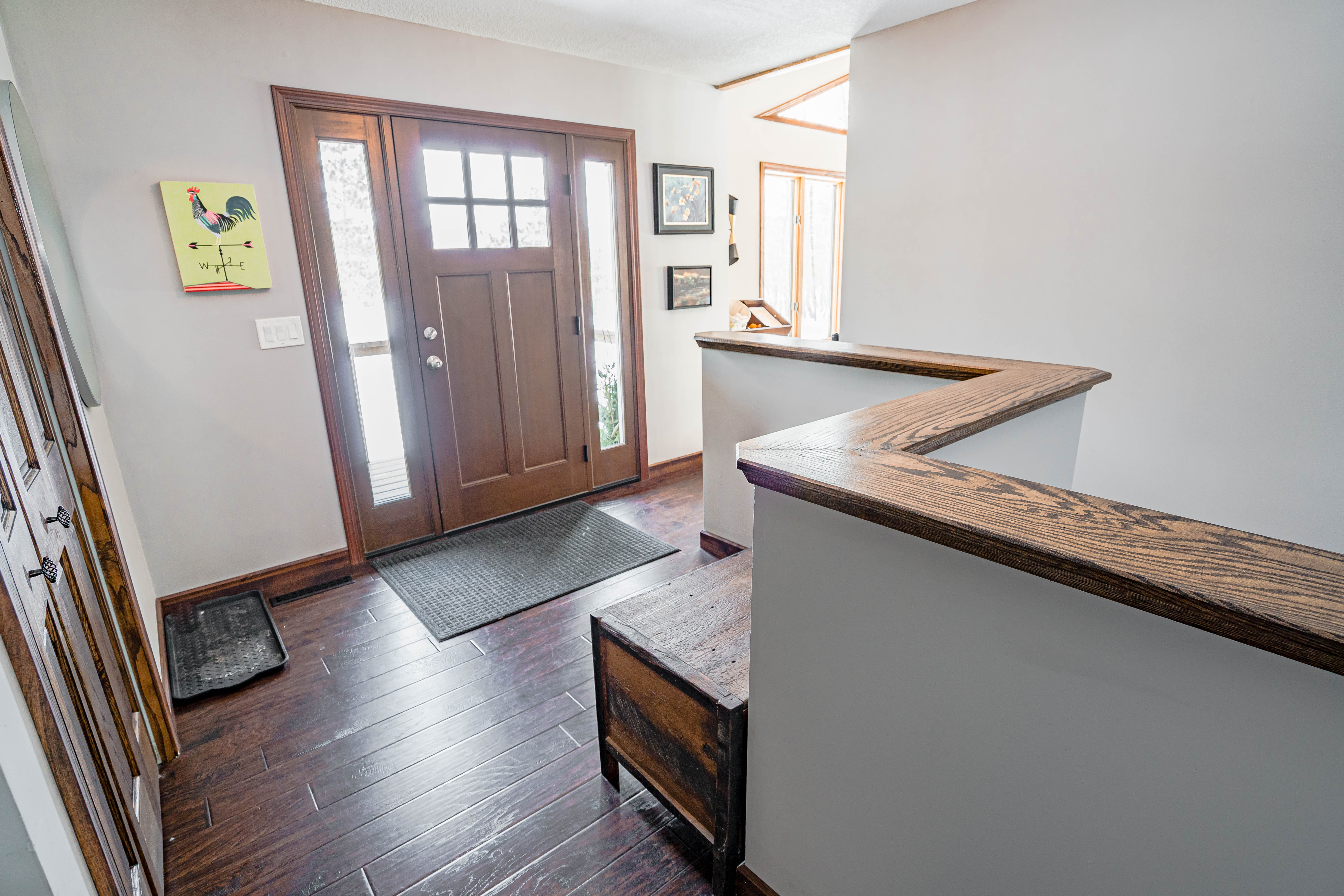 A cozy entryway with wooden finishes and a colorful rooster artwork.