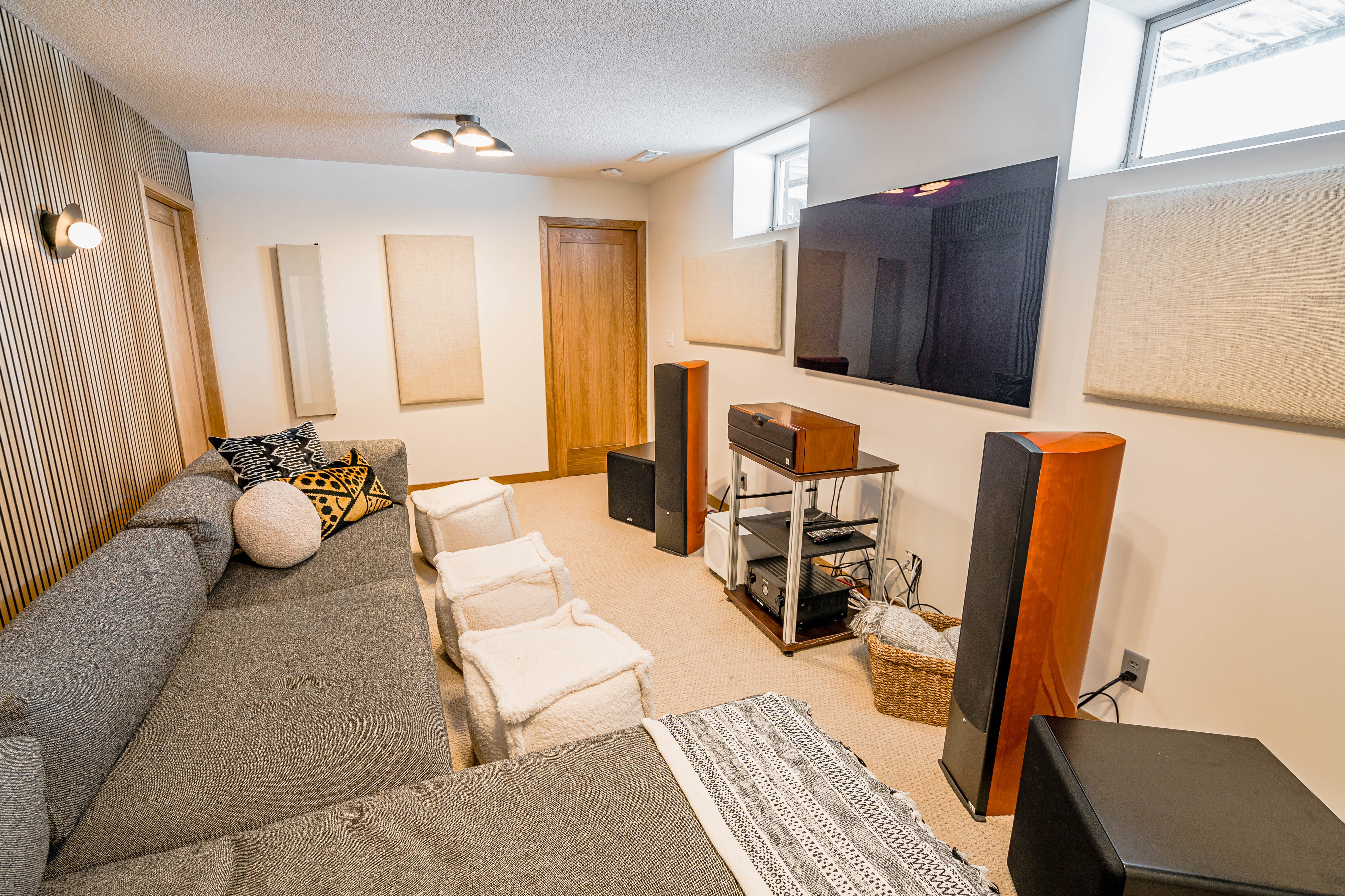 A stylish entertainment room featuring a grey sectional couch and modern audio setup.