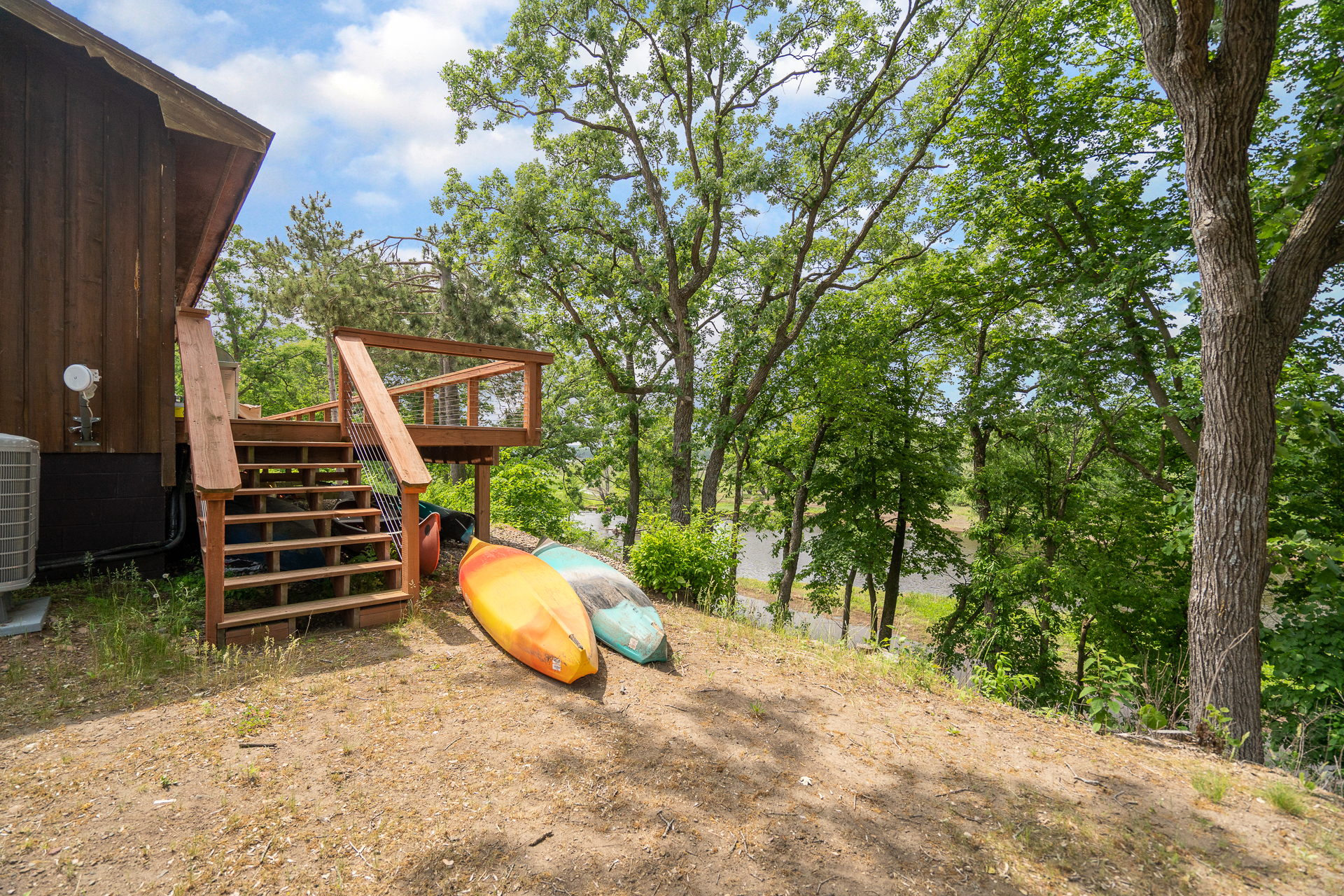 A cozy cabin with kayaks resting on the ground near a lush landscape.