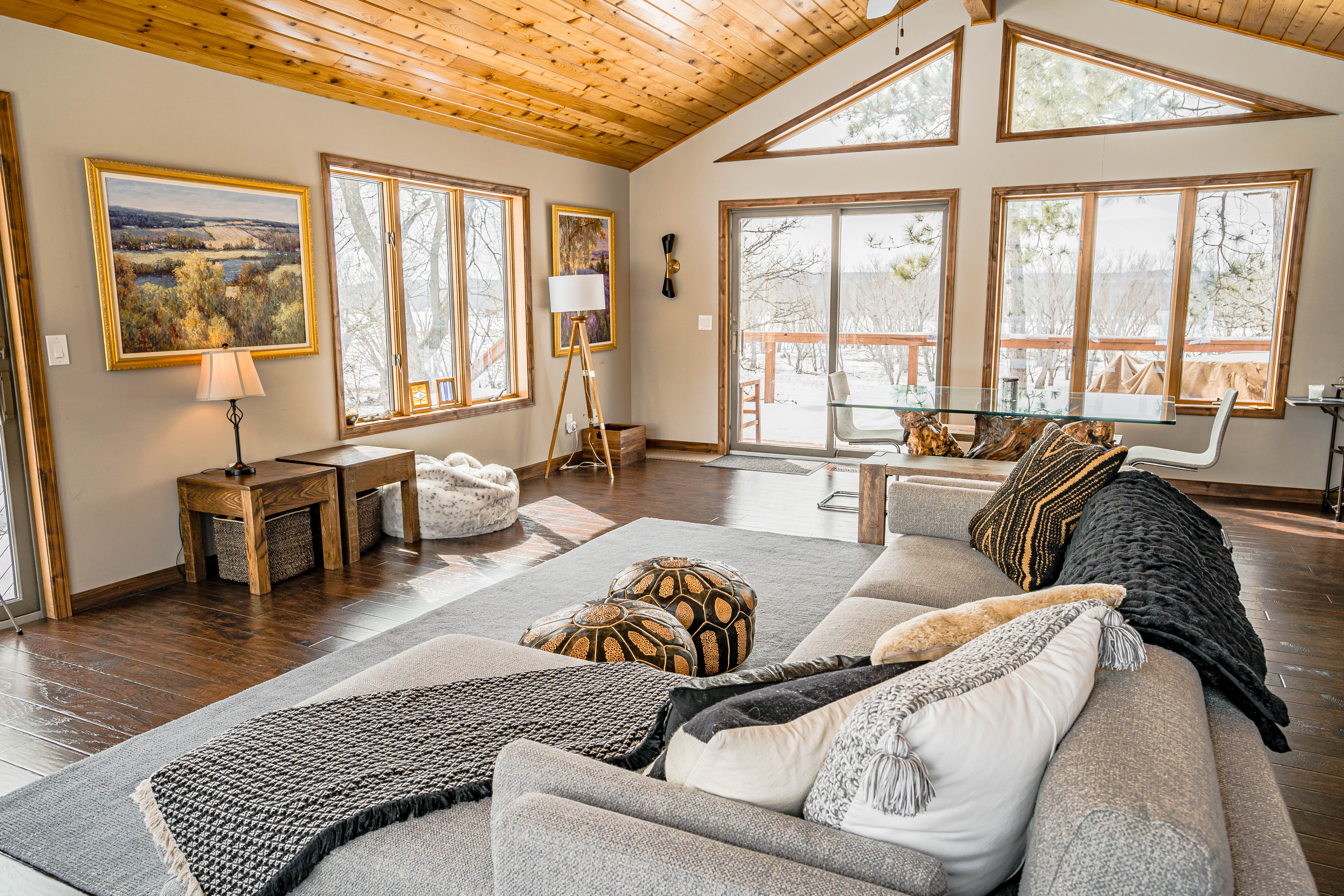 Cozy living room with high ceilings, wooden decor, and winter landscape outside.