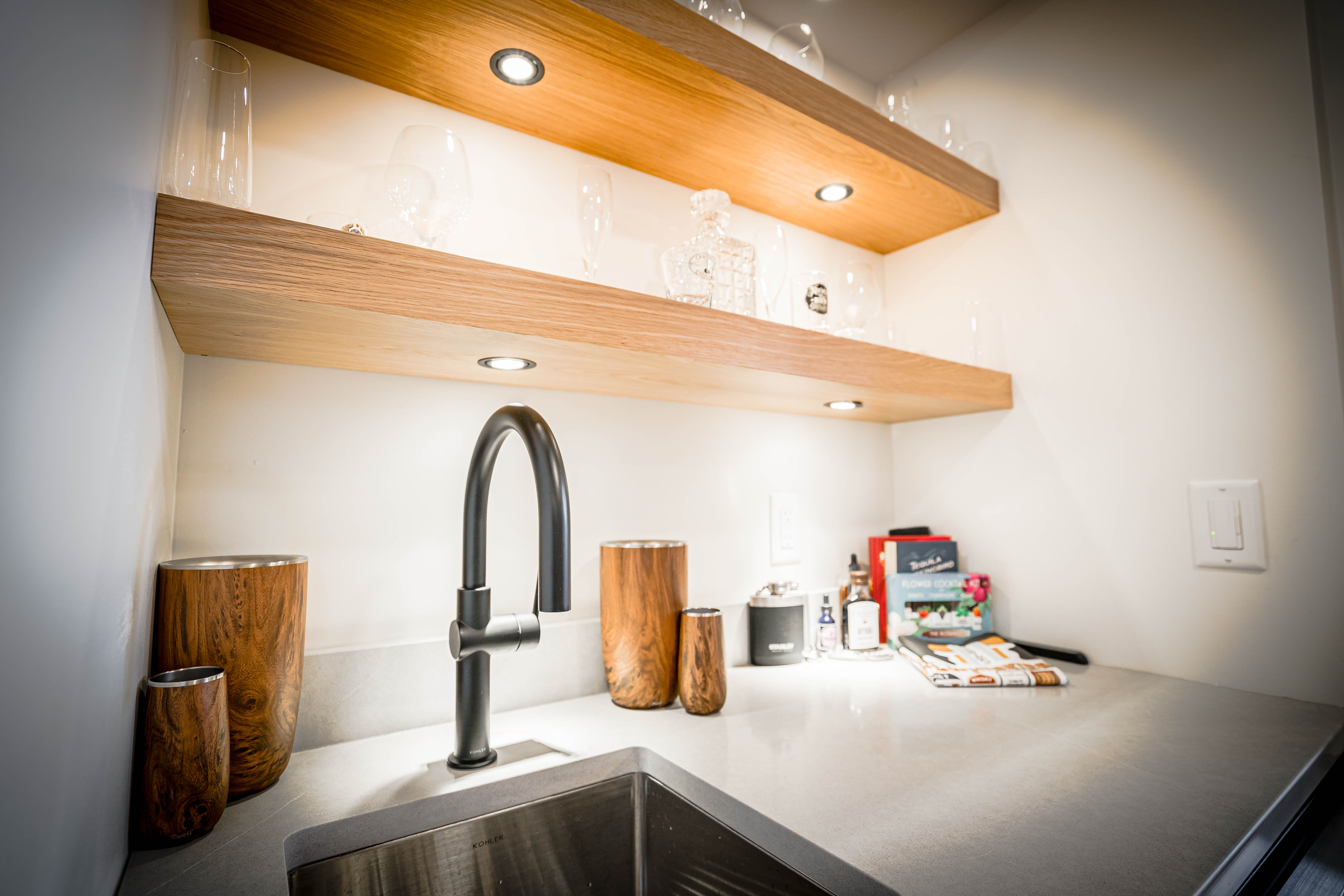 A modern kitchen nook with elegant wooden shelving and stylish barware.