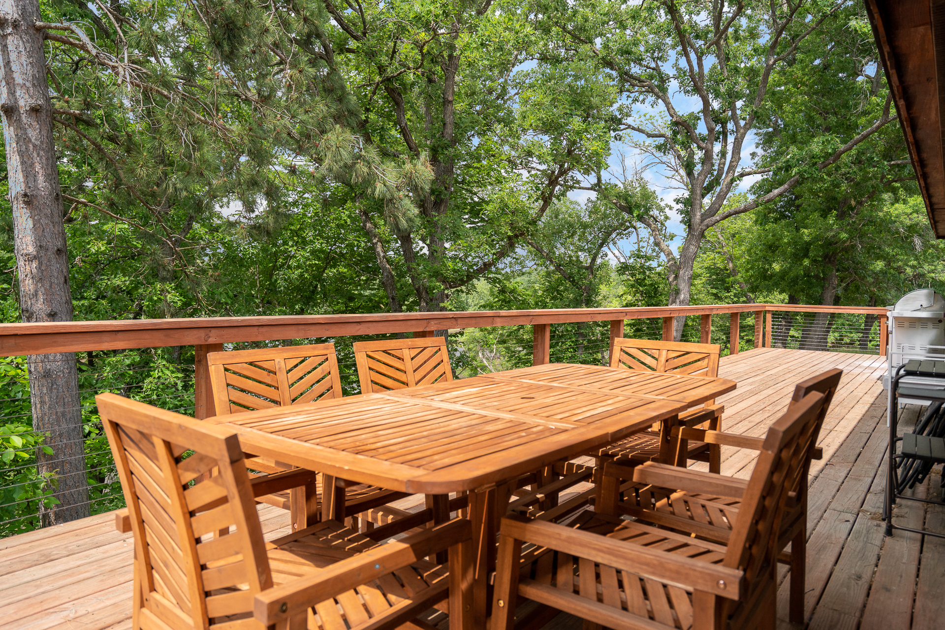 A serene wooden deck with a dining table amidst lush greenery.