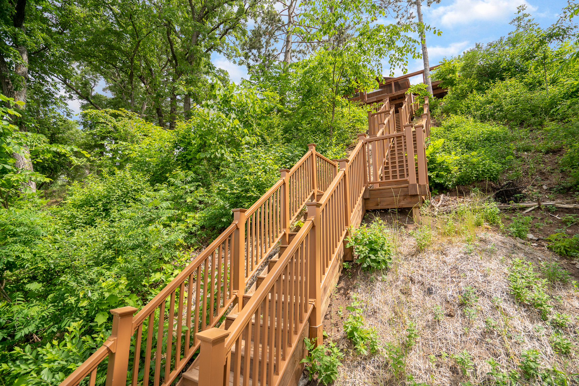A beautiful wooden staircase surrounded by lush greenery leading up a hillside.