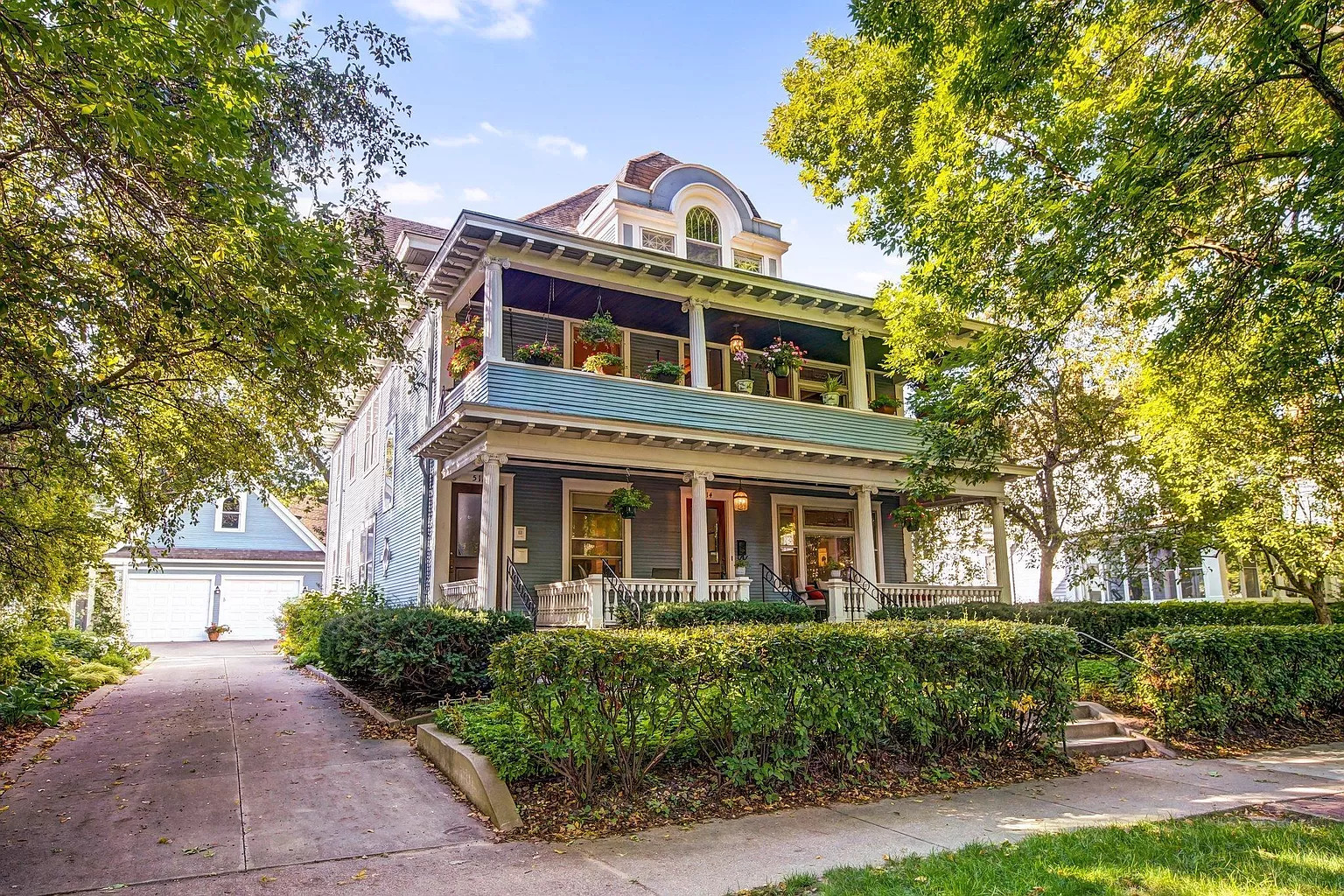 Charming historic house with a welcoming front porch and lush surroundings.