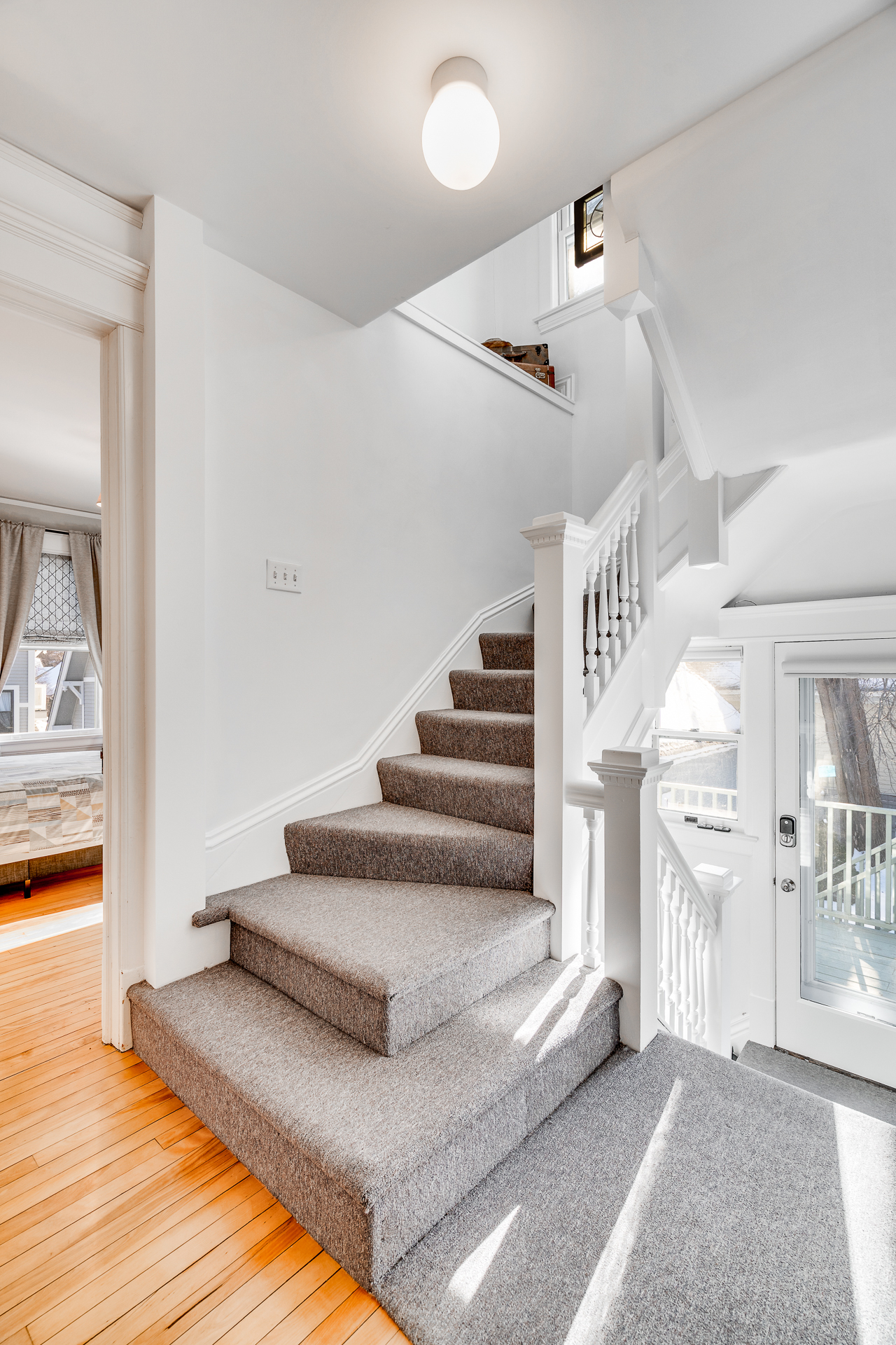 A bright and inviting interior staircase with grey carpeting and wooden floors.