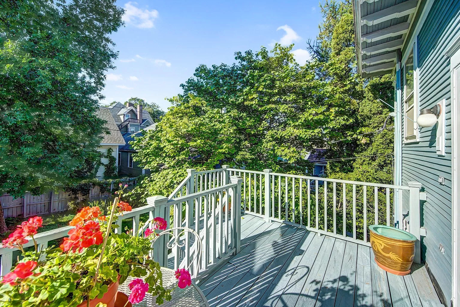 A serene balcony filled with colorful flowers and surrounded by lush greenery.